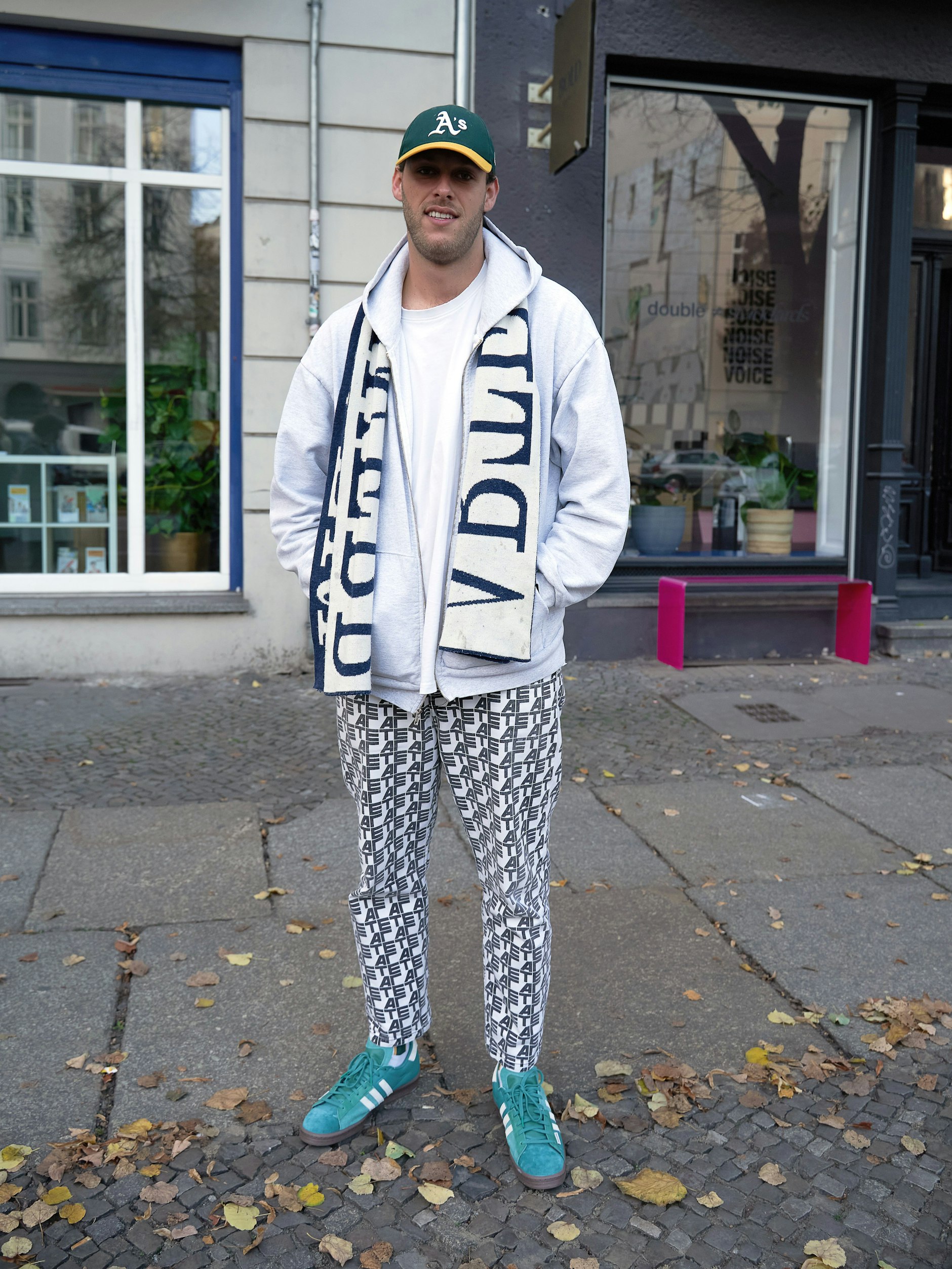Benno studiert Immobilienwirtschaft an der Hochschule Fresenius in Berlin. Sein Ziel sei es später, ungenutzte Gebäude wie leerstehende Kirchen umzufunktionieren, erklärt er. Sein Look: Cap von Oakland Athletics, Schal und Hose von Arte Antwerp, dazu ganz frisch gedroppte Darryl Brown x adidas Campus 80s „Active Green“.
