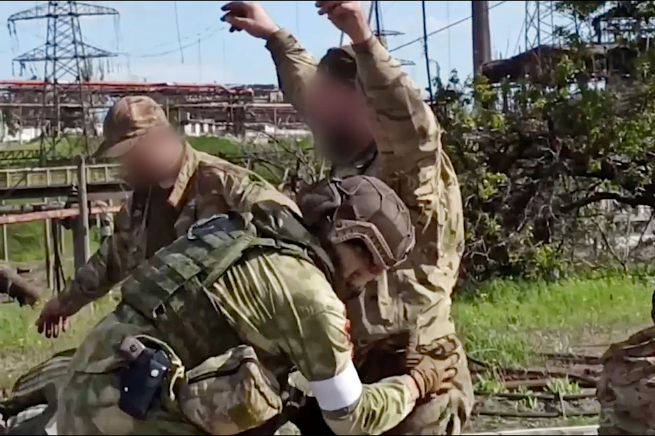 Ein ukrainischer Kämpfer aus dem Stahlwerk Azowstal wird von einem russischen Soldaten abgetastet.