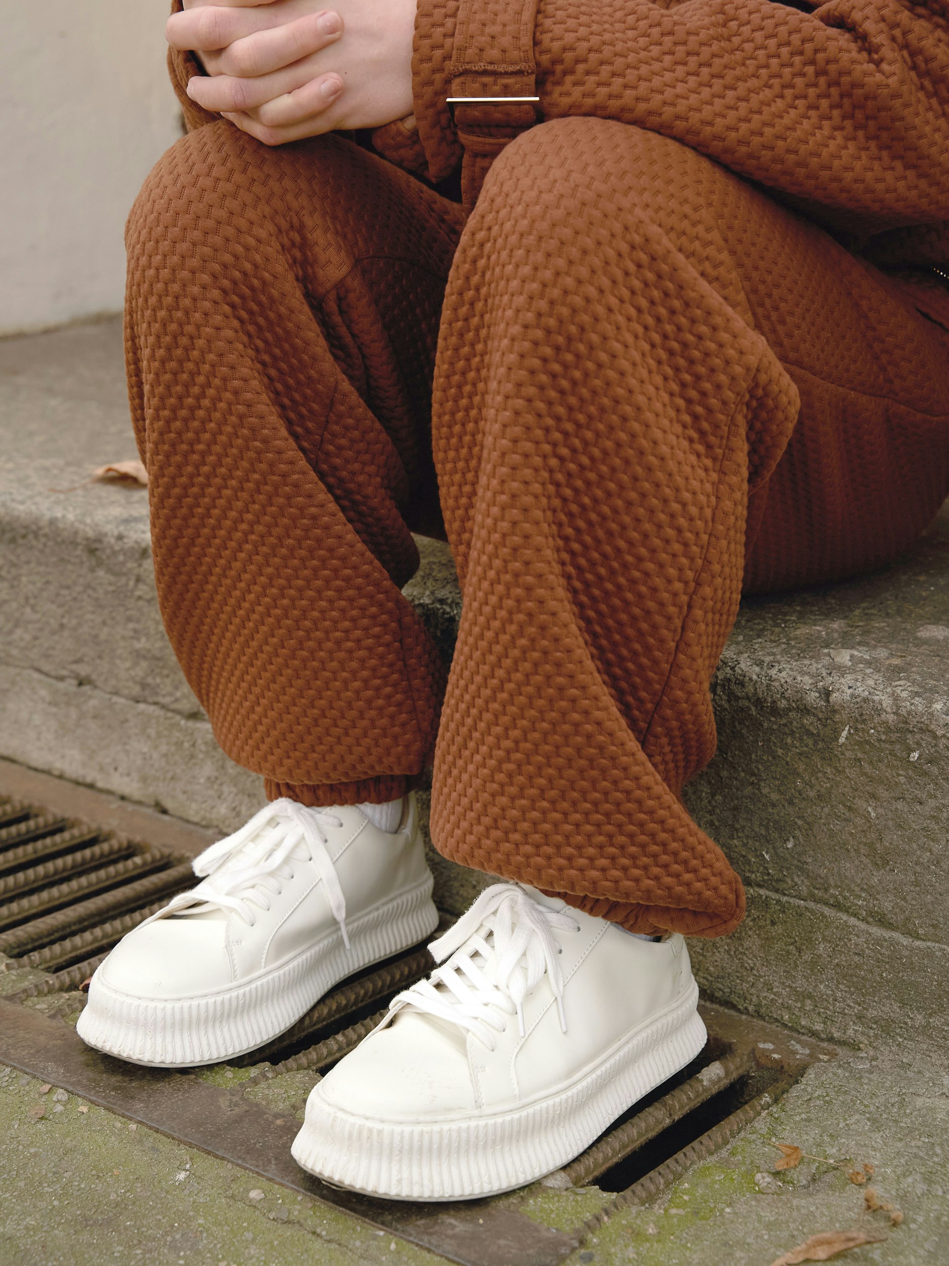 Zum braunen Anzug in Waffel-Optik trägt er schlohweiße Sneaker.