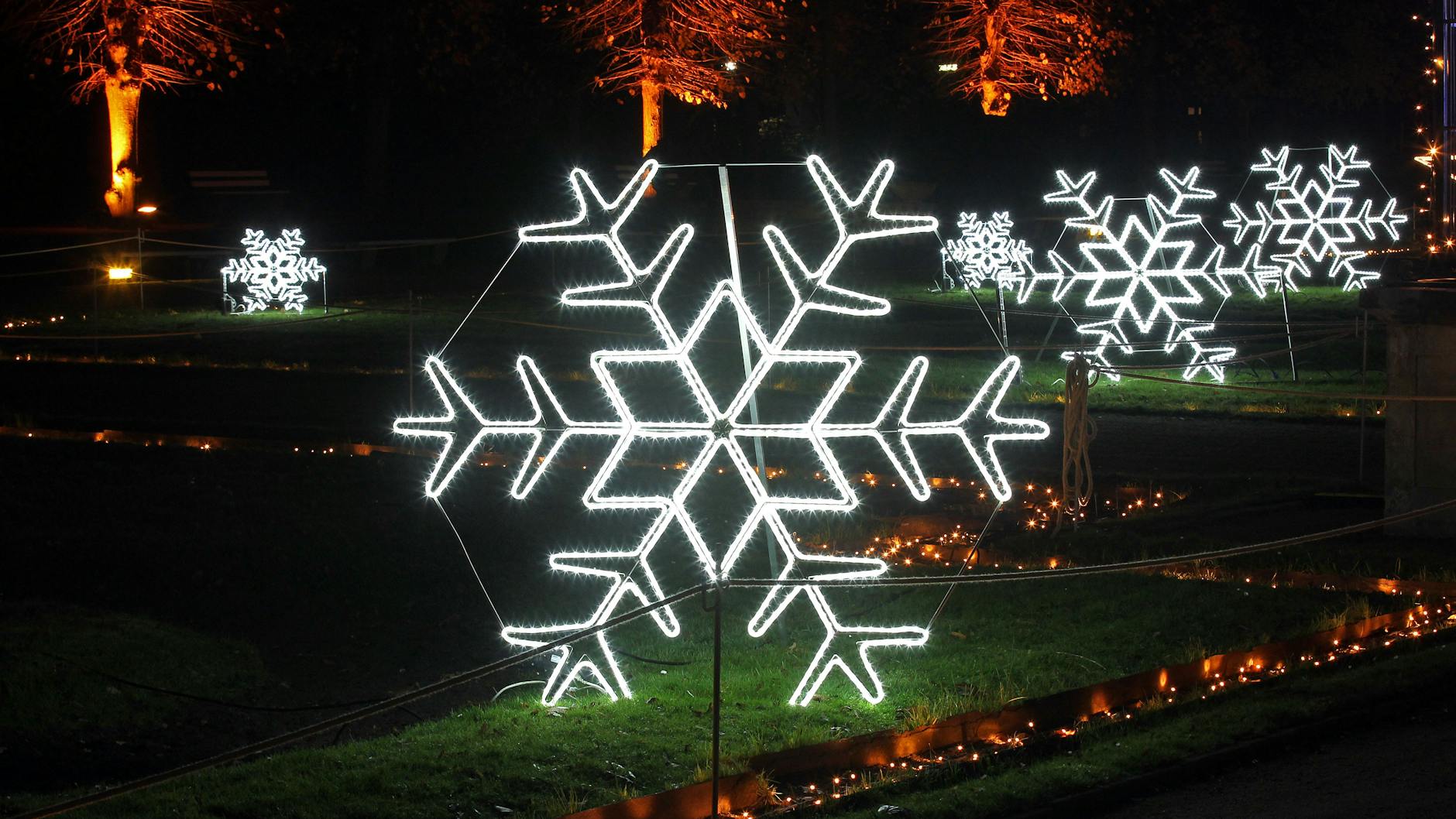 Bei der Lichtprobe am Abend erstrahlen im Schlosspark riesige Schneekristalle.