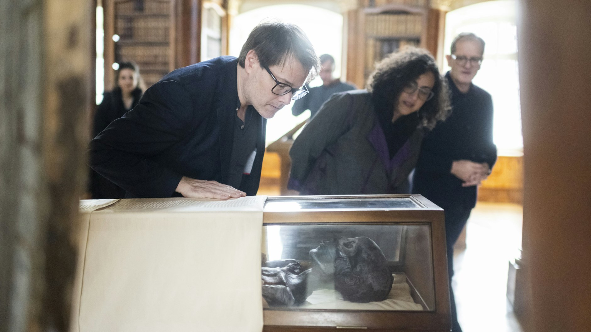 Milo Rau, Regisseur und Theaterintendant aus der Schweiz, Ägyptologin Monica Hanna und Cornel Dora, Stiftsbibliothekar aus der Schweiz, begutachten die Mumie Schepenese.