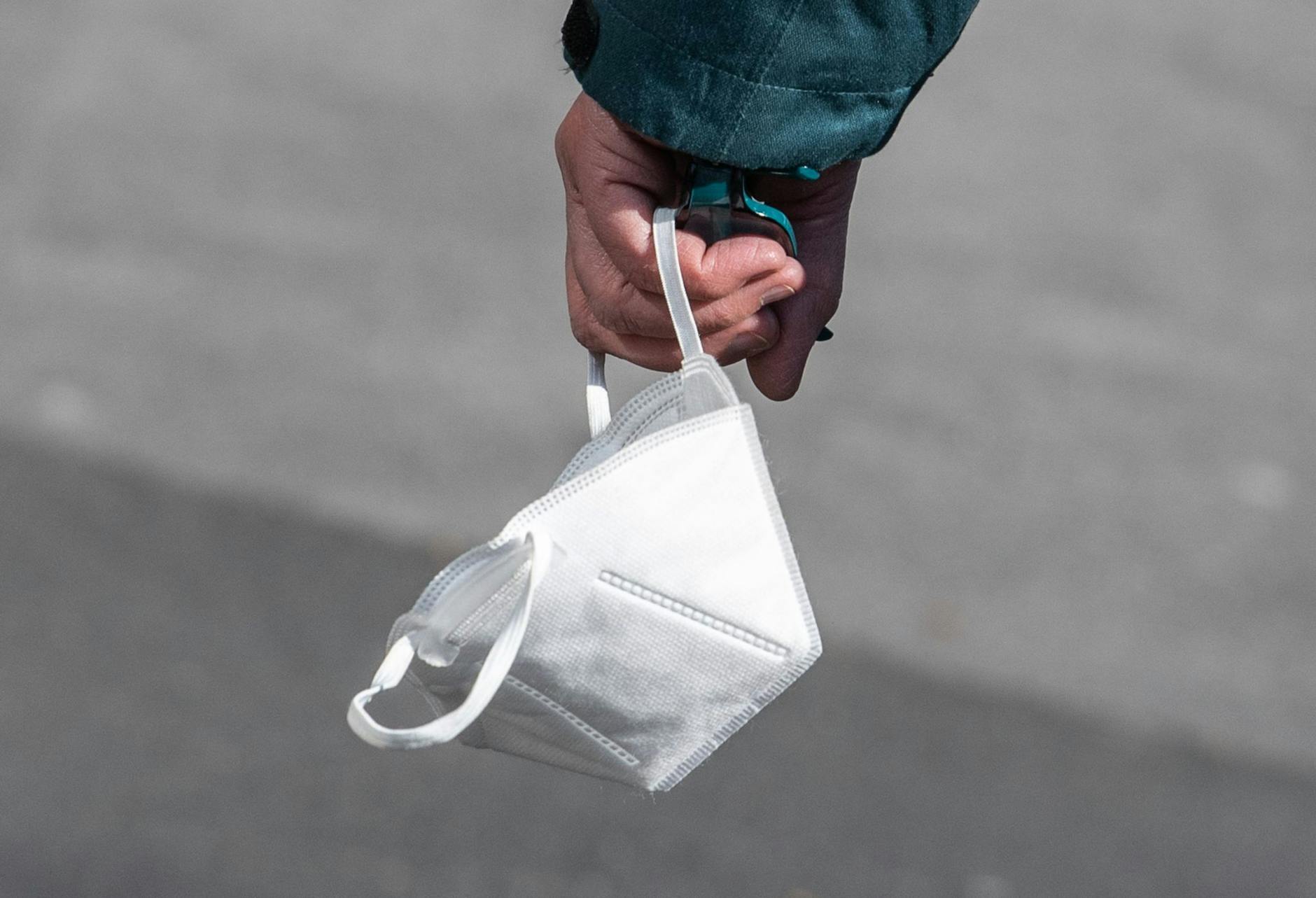 Ein Passant trägt eine FFP2-Maske in der Hand.