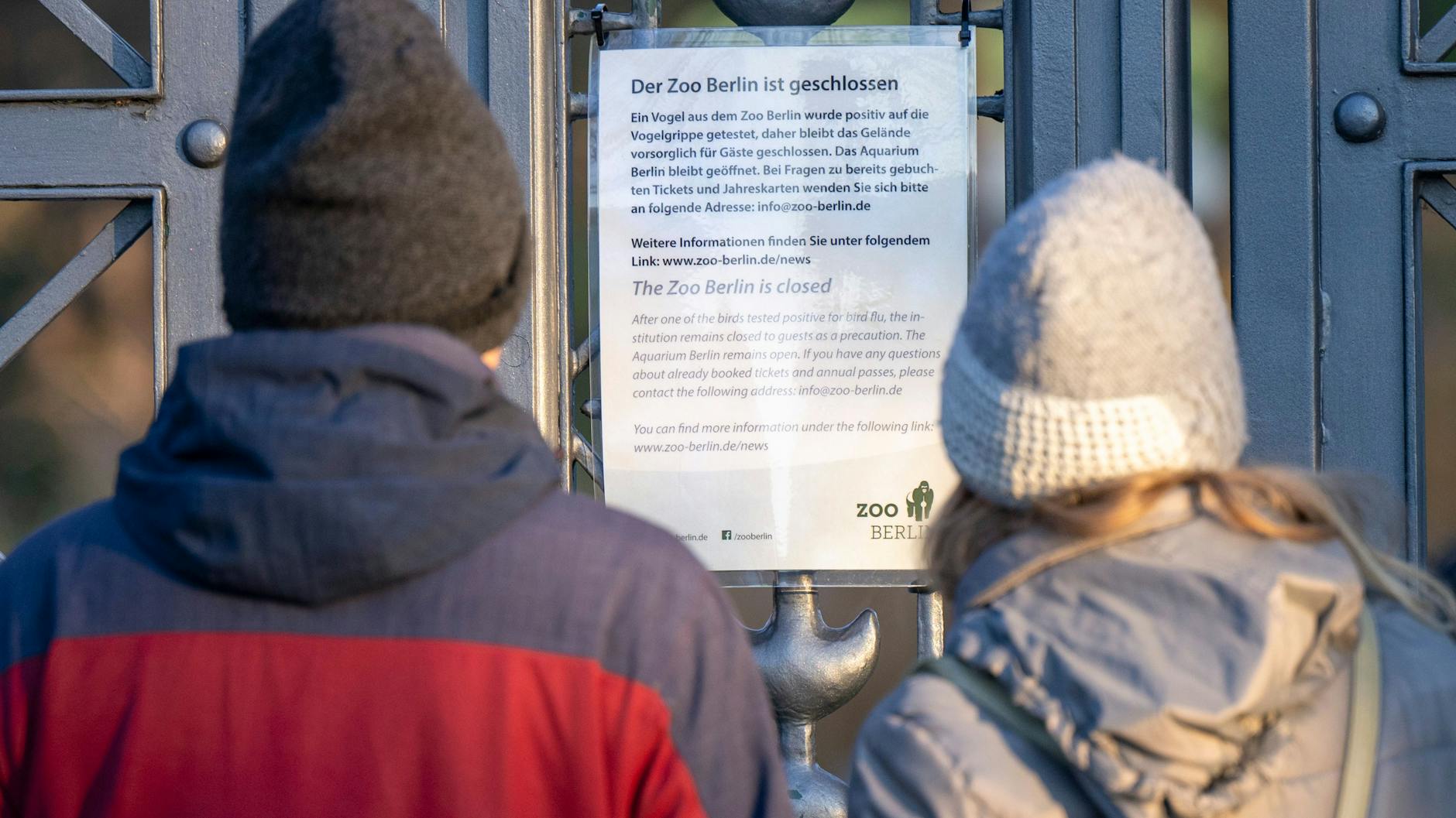 Besucher lesen den Aushang am geschlossenen Tor am Eingang zum Berliner Zoo. 