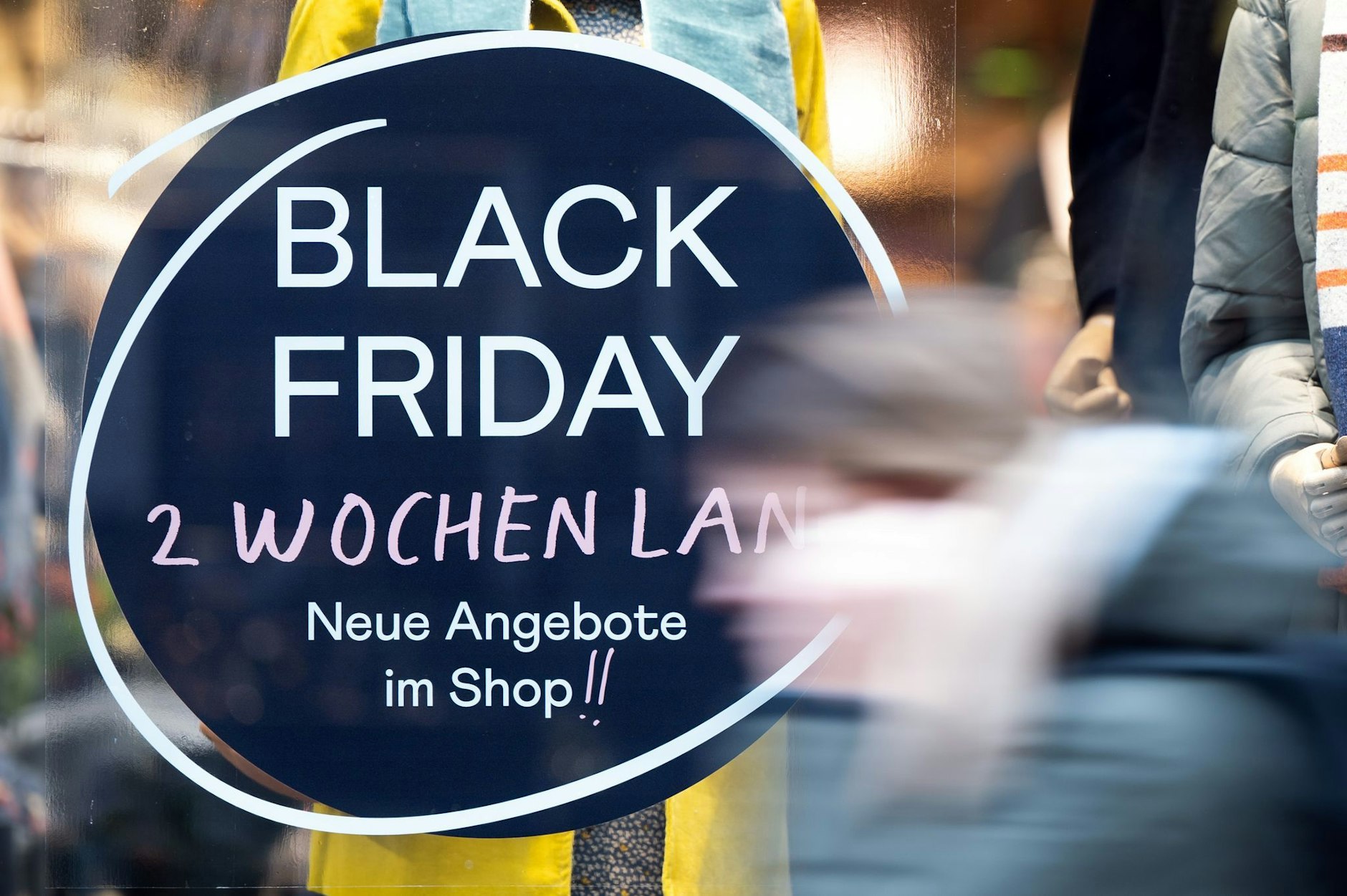 ARCHIV - Eine Frau geht an einem Geschäft vorbei, das mit Black Friday-Angeboten wirbt.  