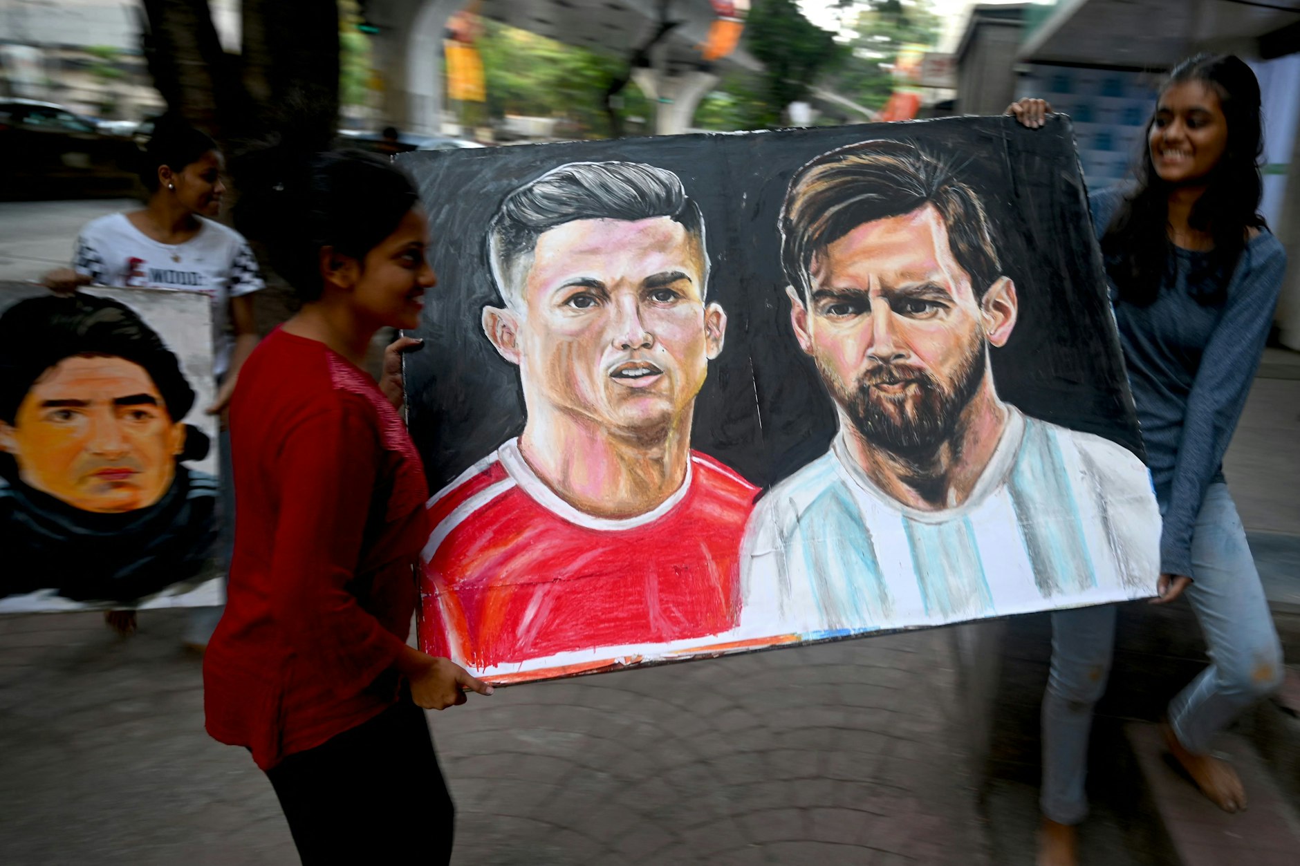 Vorbereitungen für die WM in Katar: Eine Kunstschülerin und ihre Lehrerin tragen ein Gemälde der Fußballspieler Christiano Ronaldo und Lionel Messi zu einer Ausstellung.&nbsp;