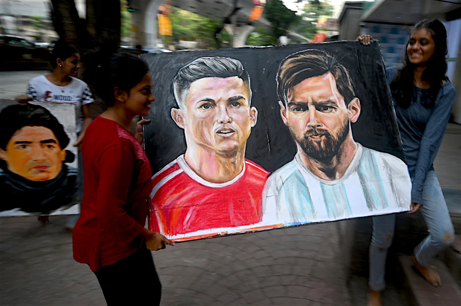 Vorbereitungen für die WM in Katar: Eine Kunstschülerin und ihre Lehrerin tragen ein Gemälde der Fußballspieler Christiano Ronaldo und Lionel Messi zu einer Ausstellung.&nbsp;