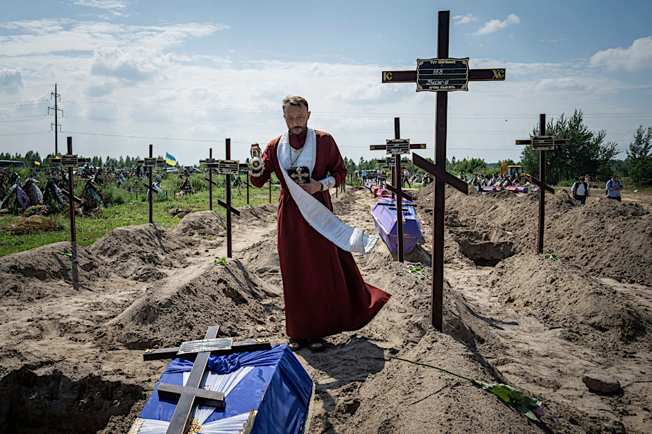 Ein orthodoxer Priester betet in der Nähe der Särge von nicht identifizierten Zivilisten, die von russischen Truppen getötet wurden.&nbsp;