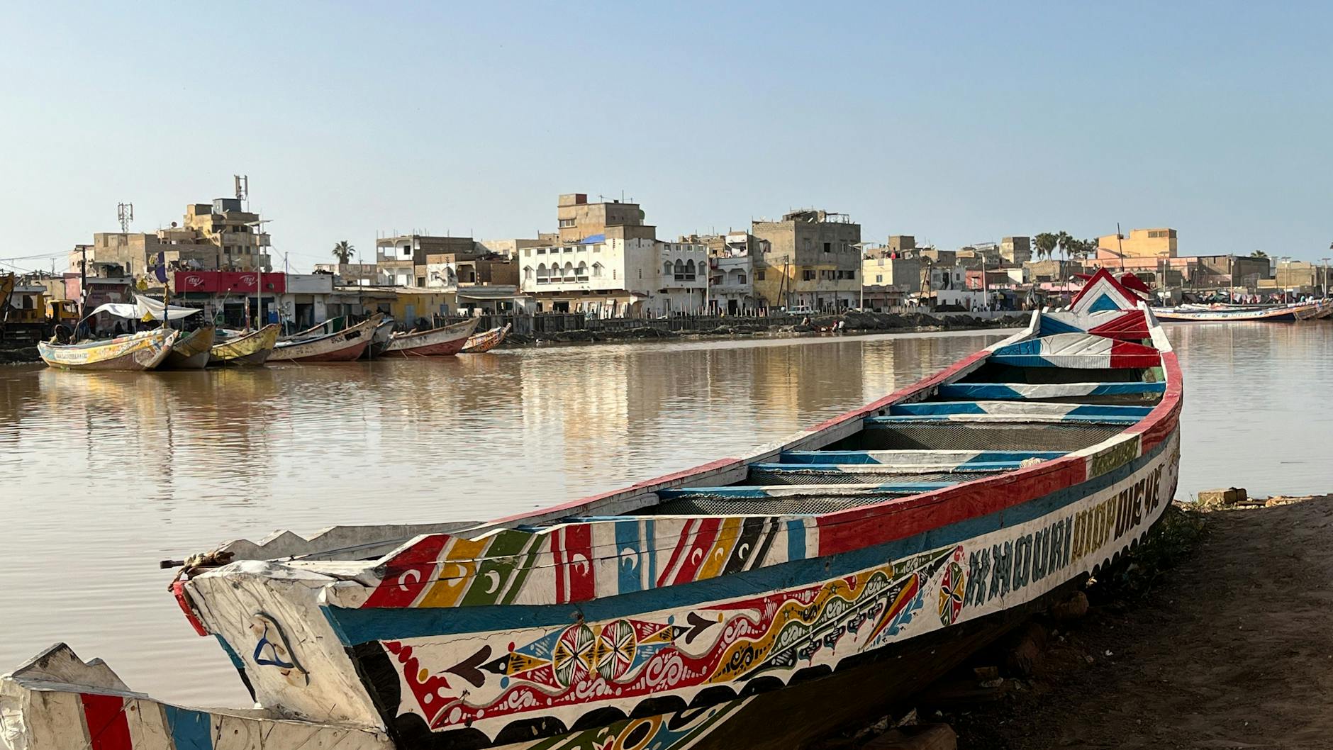 Eine bunt bemalte, für Westafrika typische Piroge liegt am Ufer des Senegal-Flusses.