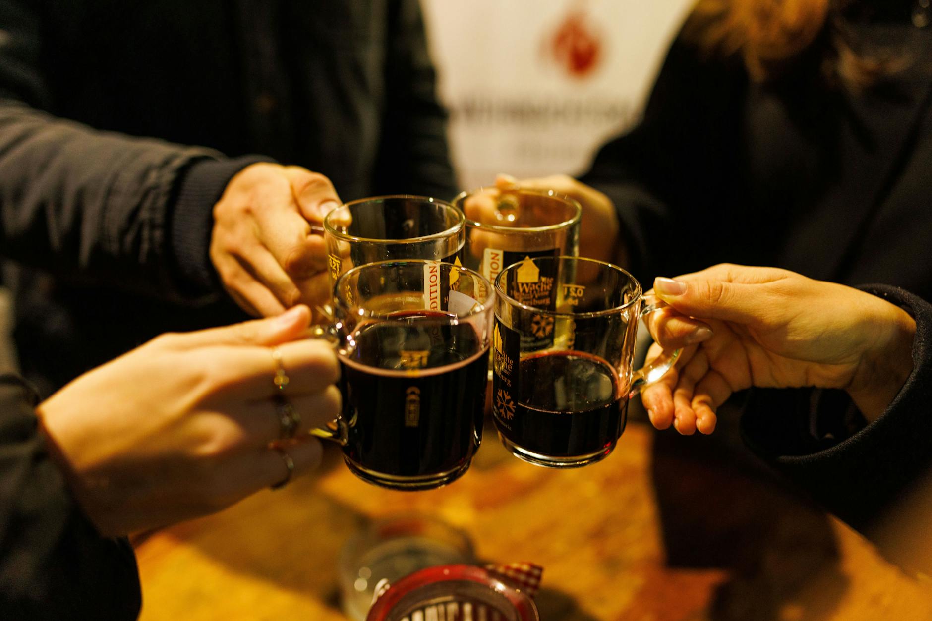 Vier Menschen stoßen mit weißem und rotem Glühwein an.