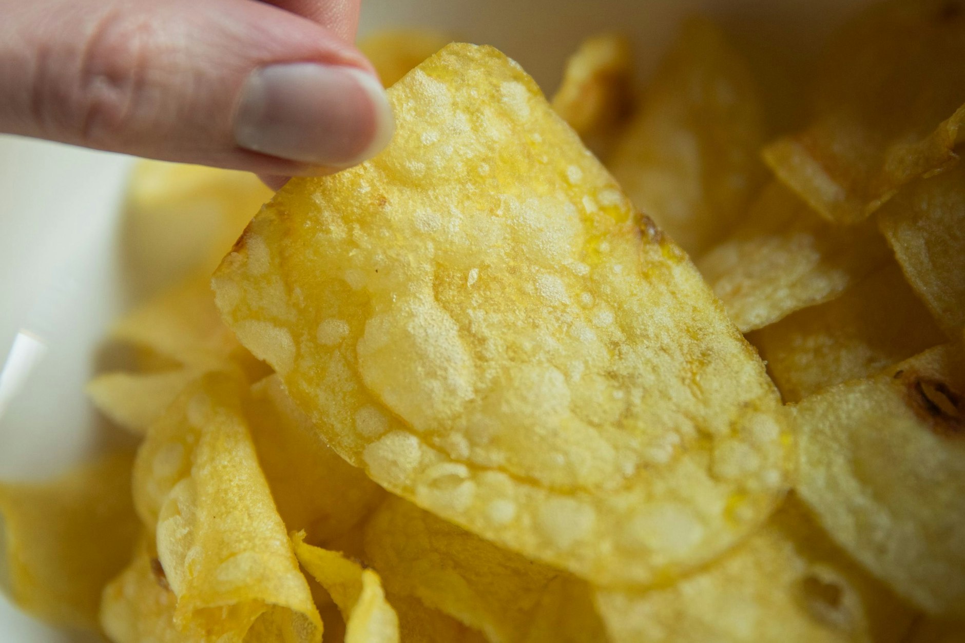 Eine Hand greift beim Fußall-Gucken nach Kartoffelchips. Hat sie sich selbstständig gemacht?