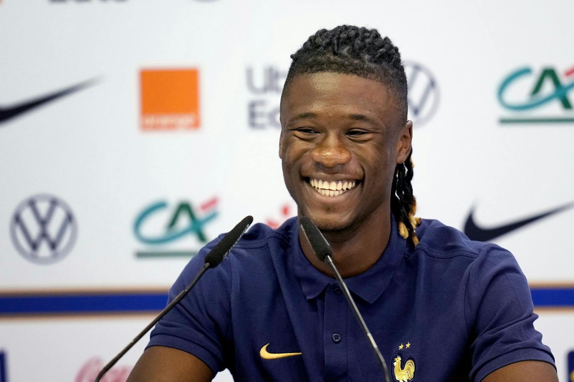 Der französische Nationalspieler Eduardo Camavinga lächelt, während er bei einer Pressekonferenz auf dem Podium sitzt.