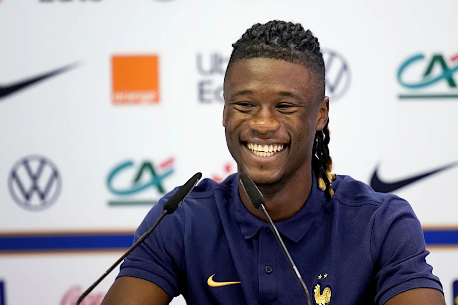 Der französische Nationalspieler Eduardo Camavinga lächelt, während er bei einer Pressekonferenz auf dem Podium sitzt.  