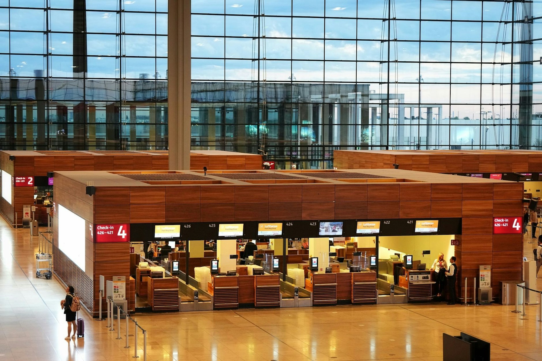 Check-in-Schalter im Terminal 1 auf dem Flughafen Berlin Brandenburg. Im Hintergrund die großen Glasfassaden des Baus.&nbsp;