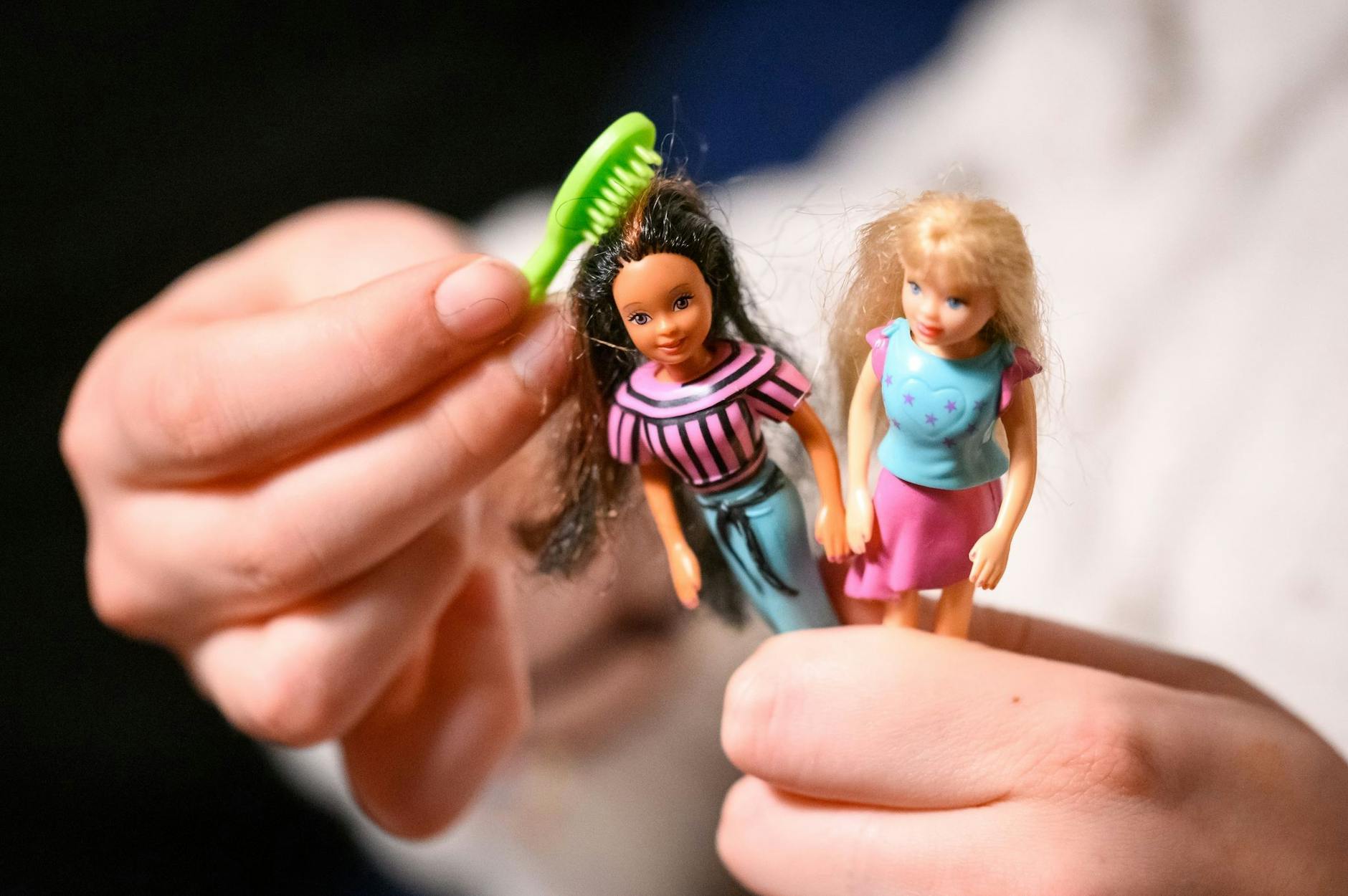 ILLUSTRATION - Eine junge Frau kämmt die Haare von zwei der größeren Polly Pocket Puppen.