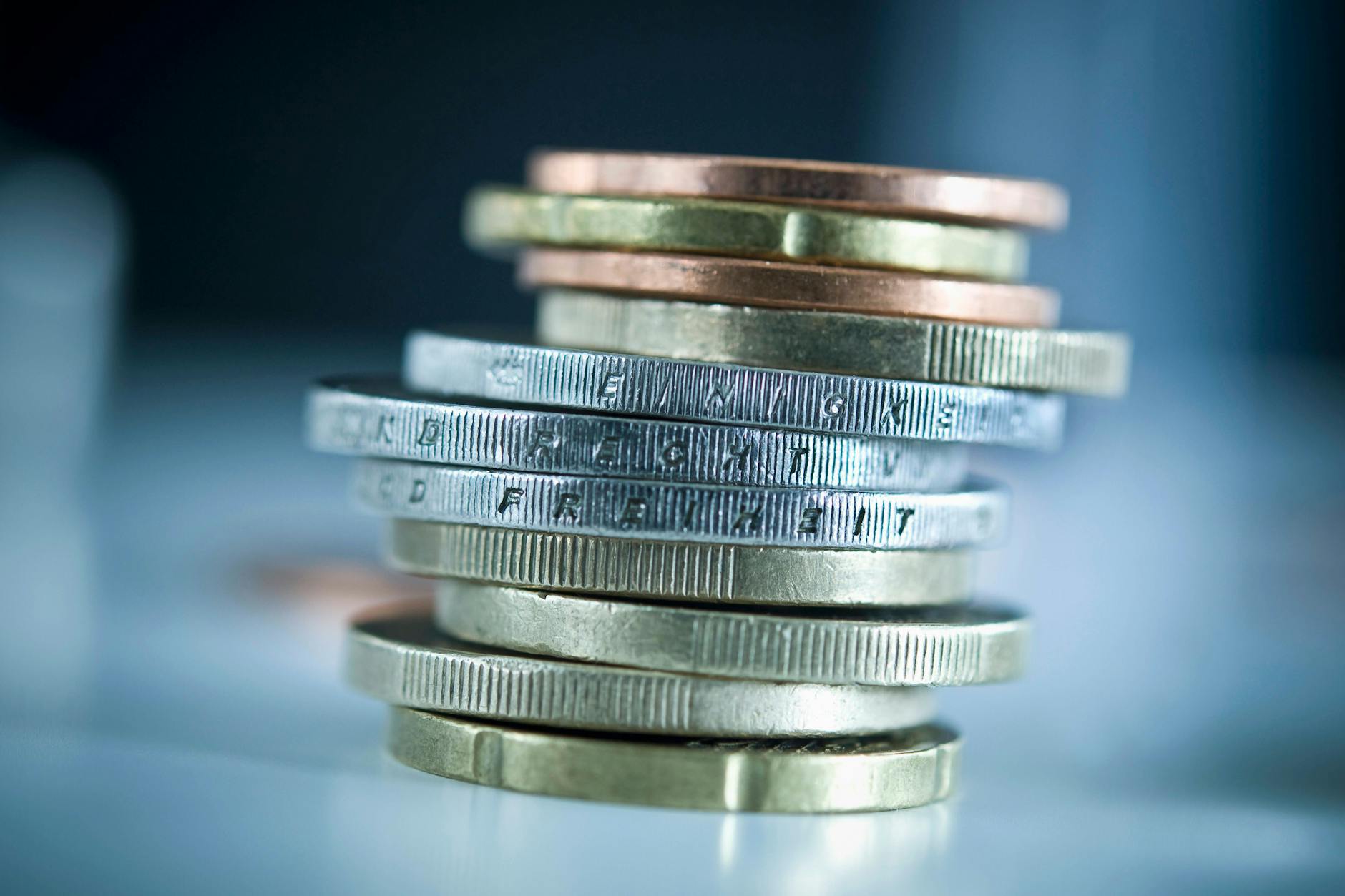 Euro-Münzen liegen gestapelt auf einem Tisch. 