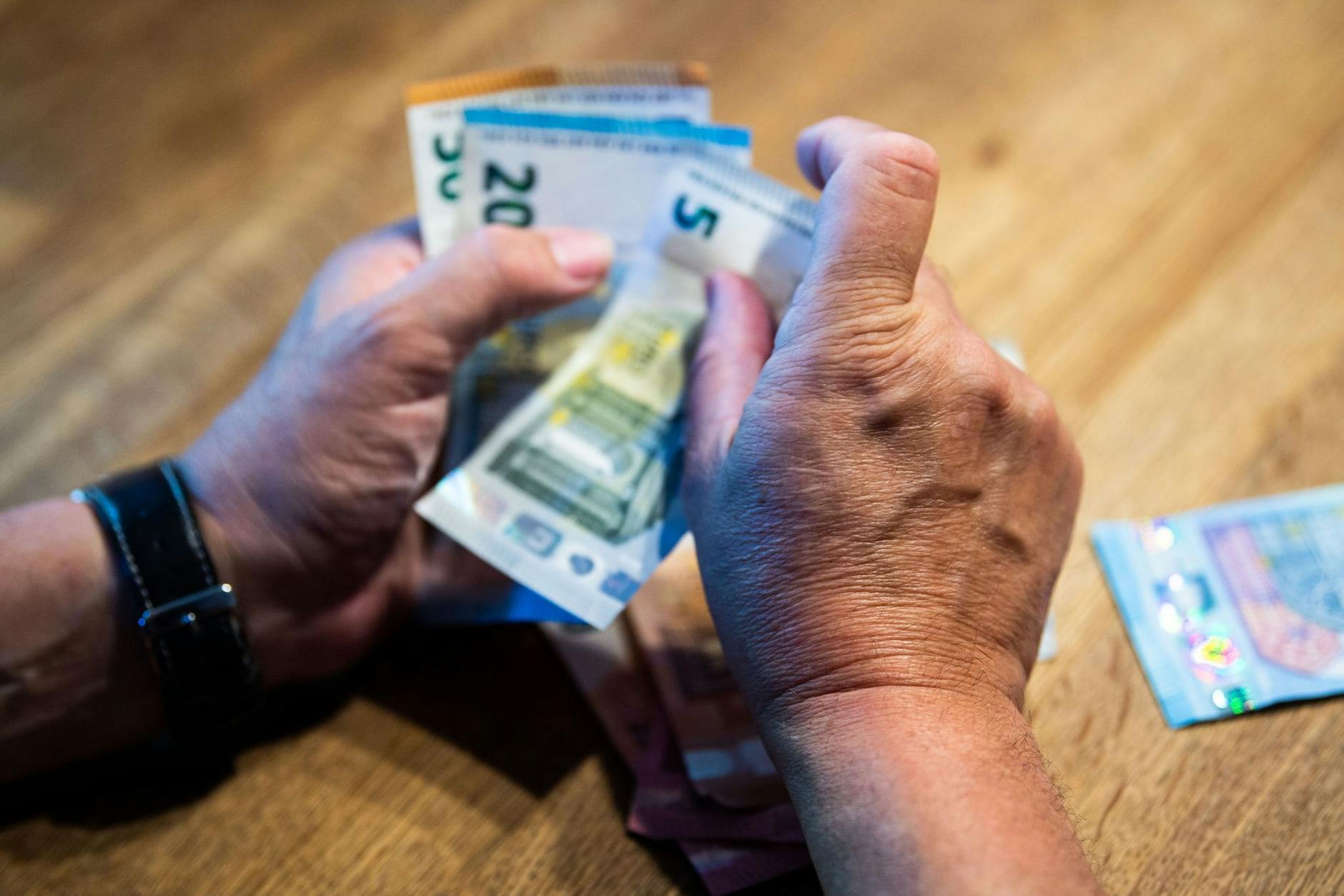 ARCHIV - Ein älterer Mann zählt Geld an einem Tisch.