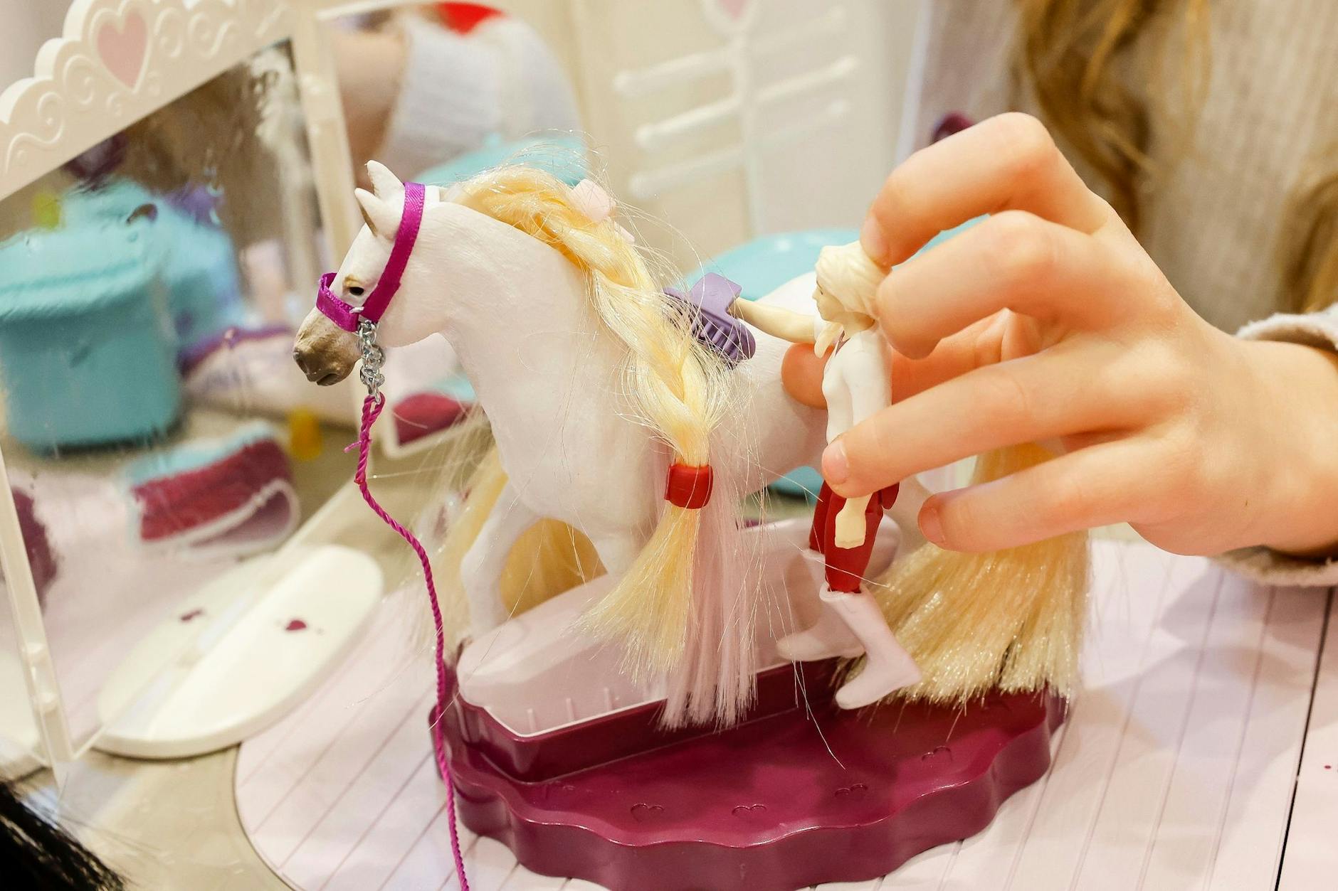 Ein Mädchen spielt auf der Pressekonferenz mit einem Beauty-Salon für Spielzeugpferde von Schleich.