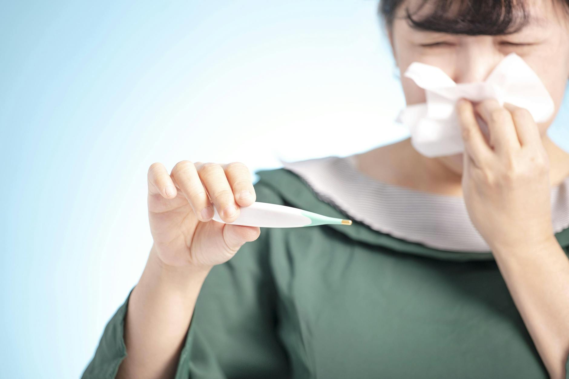 Eine verschnupfte Frau mit Fieberthermometer: Deutschland erwartet eine starke Grippewelle.