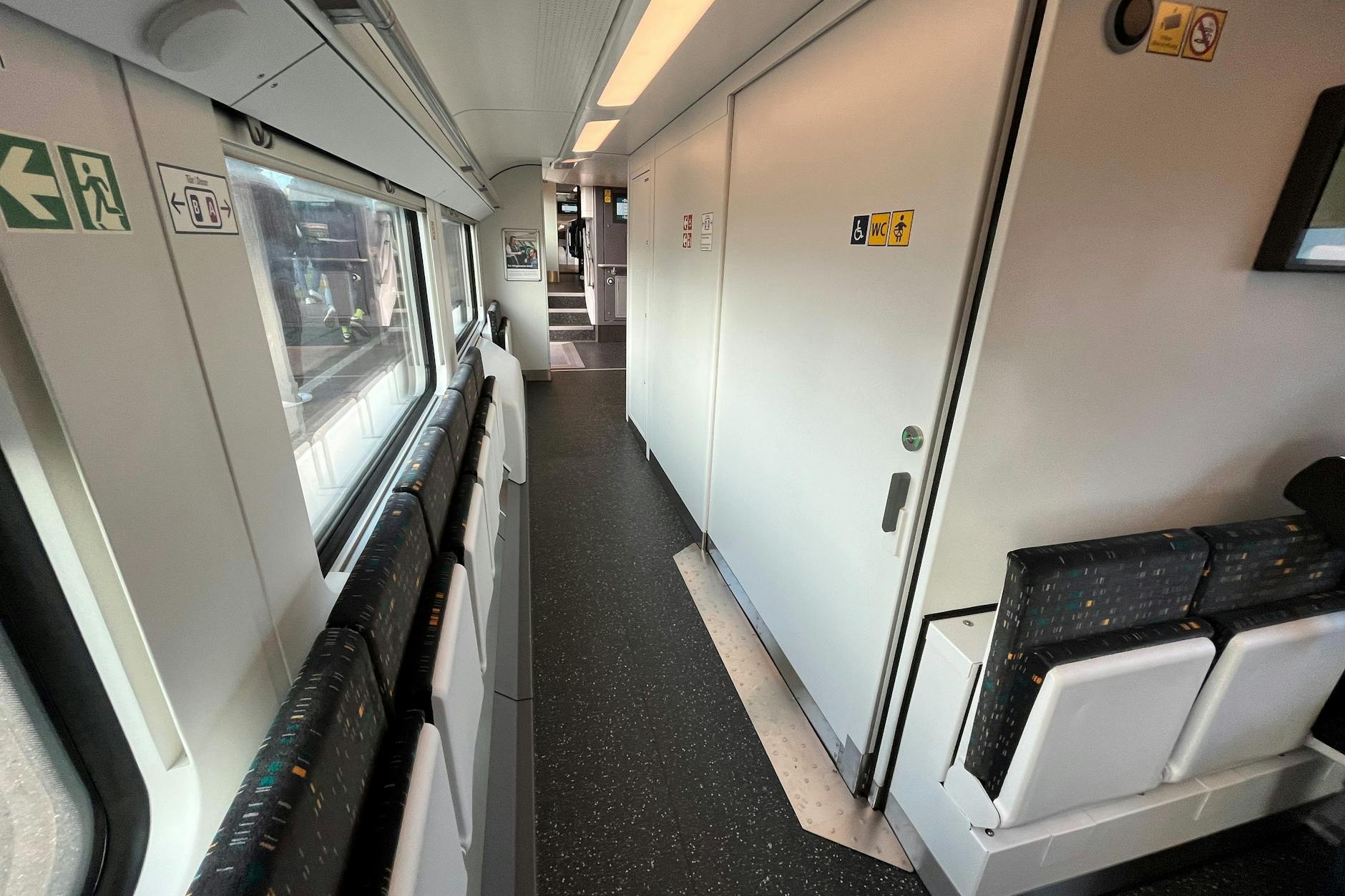 An manchen Stellen ist der Gang ziemlich schmal. Neben der Behindertentoilette sind Klappsitze angebracht. Ein Schild mahnt: „Durchgang bitte freihalten. Bei Bedarf aufstehen.“