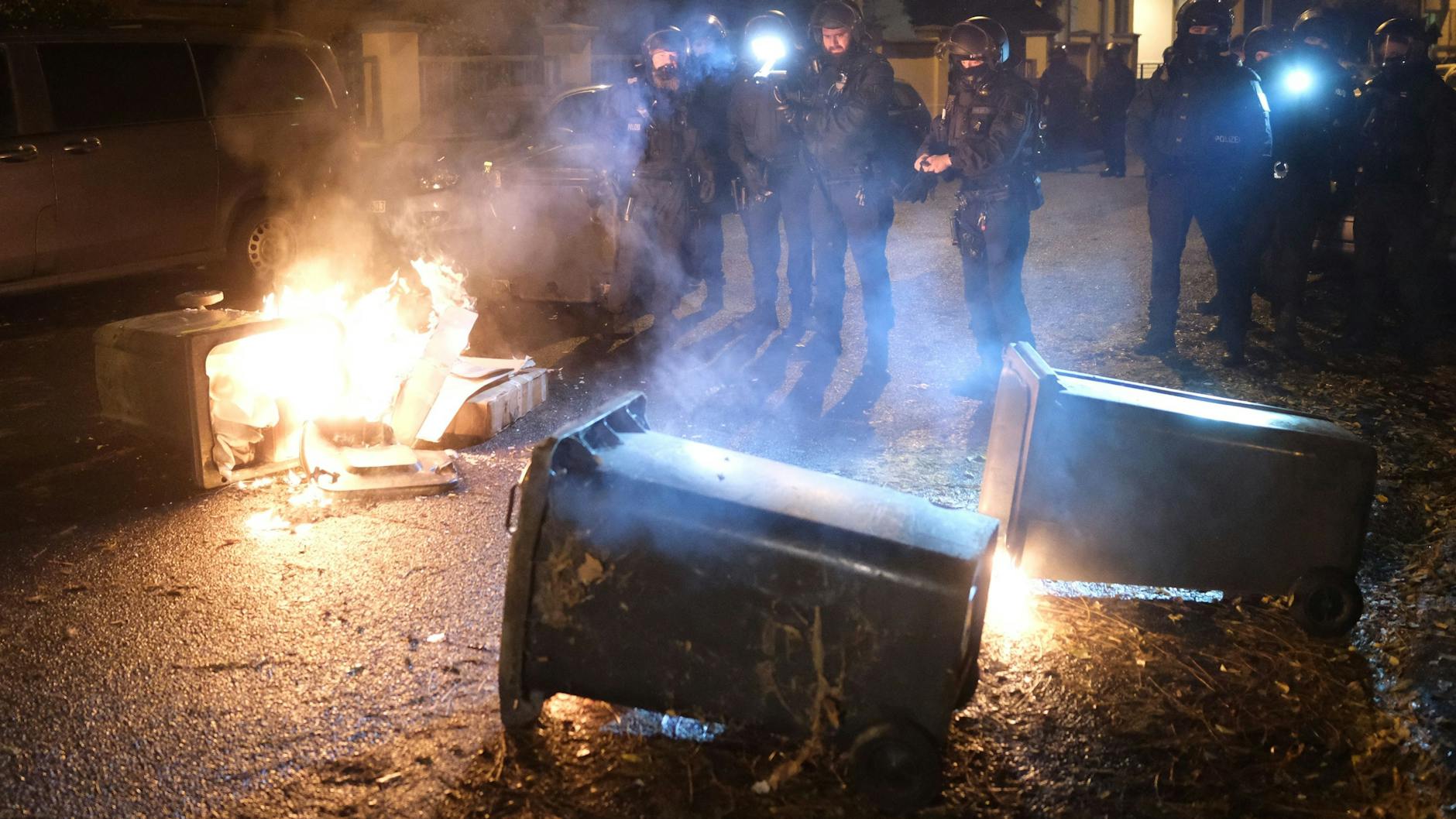Polizisten stehen an brennenden Müllcontainern. Teilnehmer einer linken Demonstration blockierten in Leipzig einen rechten Aufmarsch unter dem Motto "Ami go home". 