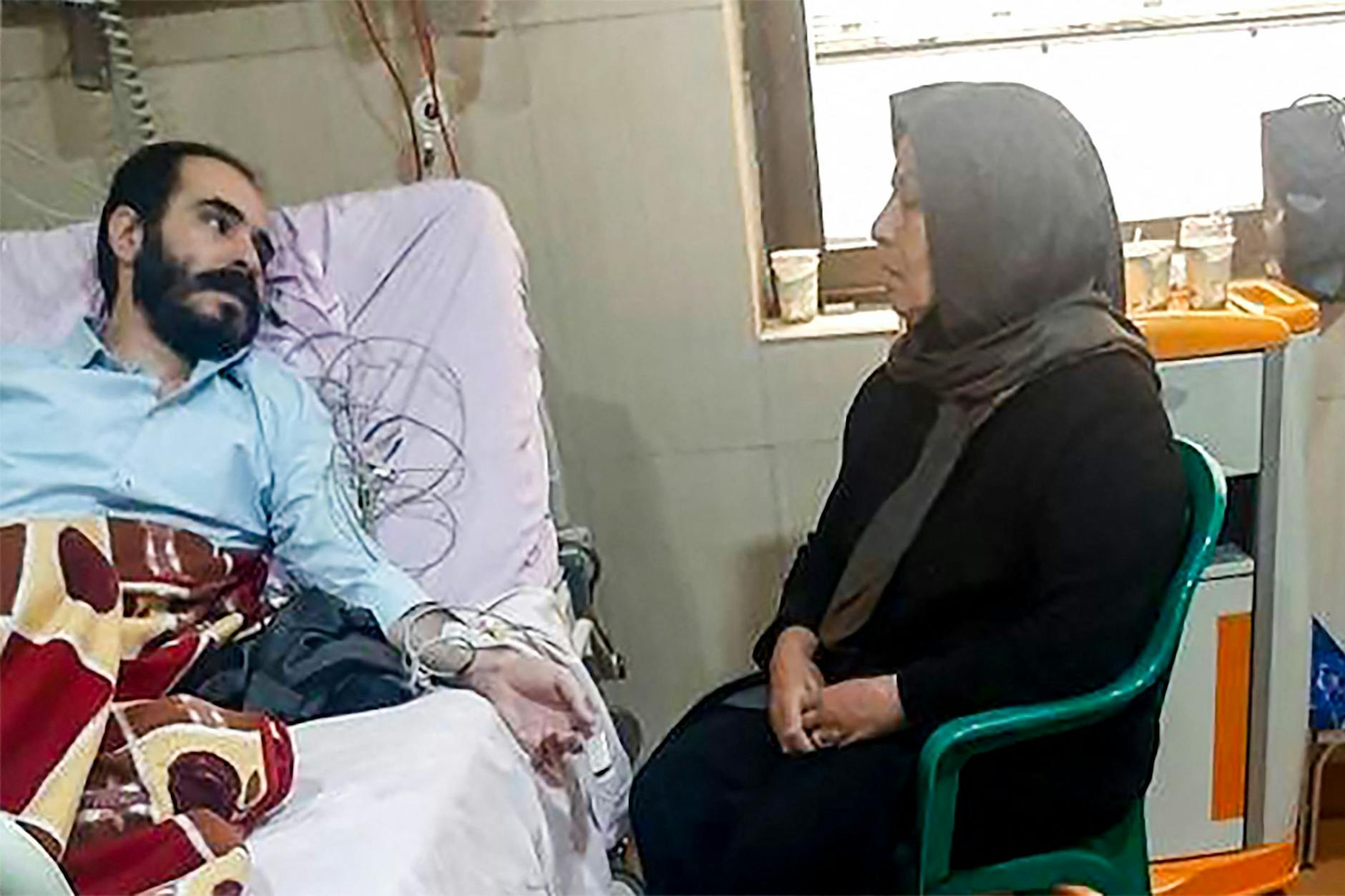 Menschenrechtsaktivist Hossein Ronaghi liegt am 14. November 2022 in Teheran in einem Krankenhausbett, neben ihm sitzt seine Mutter.