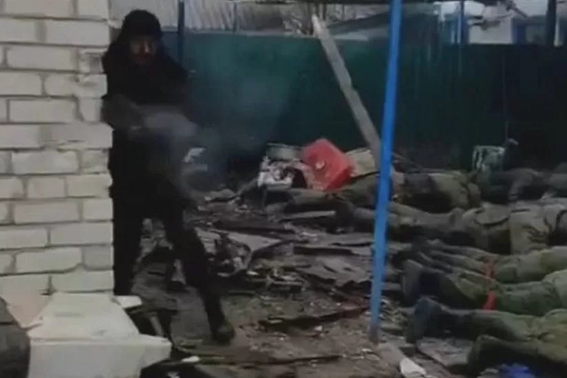 Ein bewaffneter Mann richtet das Feuer auf die Person mit der Filmkamera. Im Hintergrund die russischen Soldaten, die sich ergeben haben.