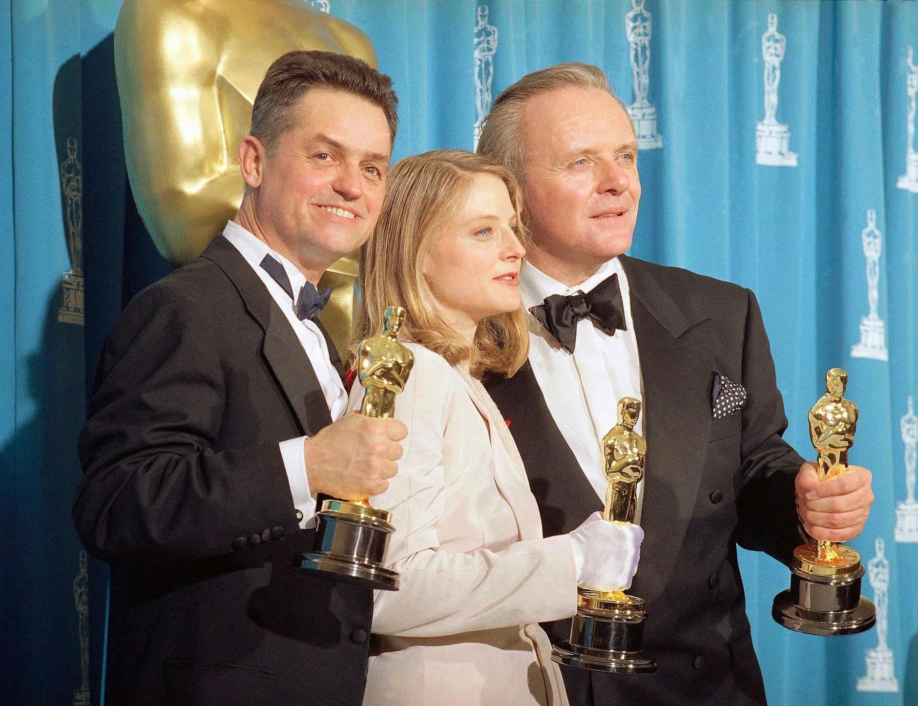 ARCHIV - Der Regisseur Jonathan Demme (l-r), die Schauspielerin Jody Foster und der Schauspieler Anthony Hopkins bei der Oscarverleihung 1992.