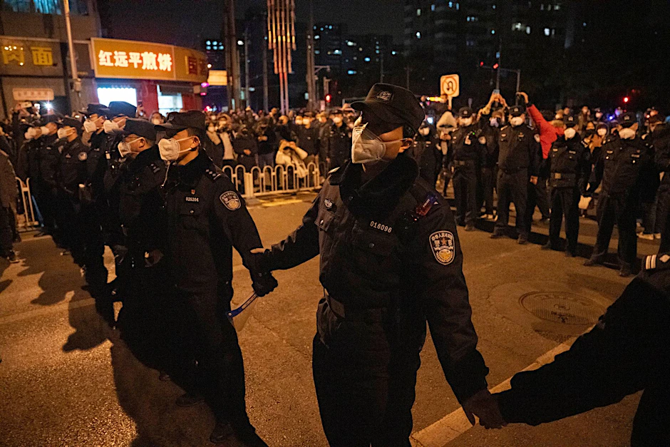 Polizisten bilden eine Linie, um Demonstranten in Peking zu stoppen.  