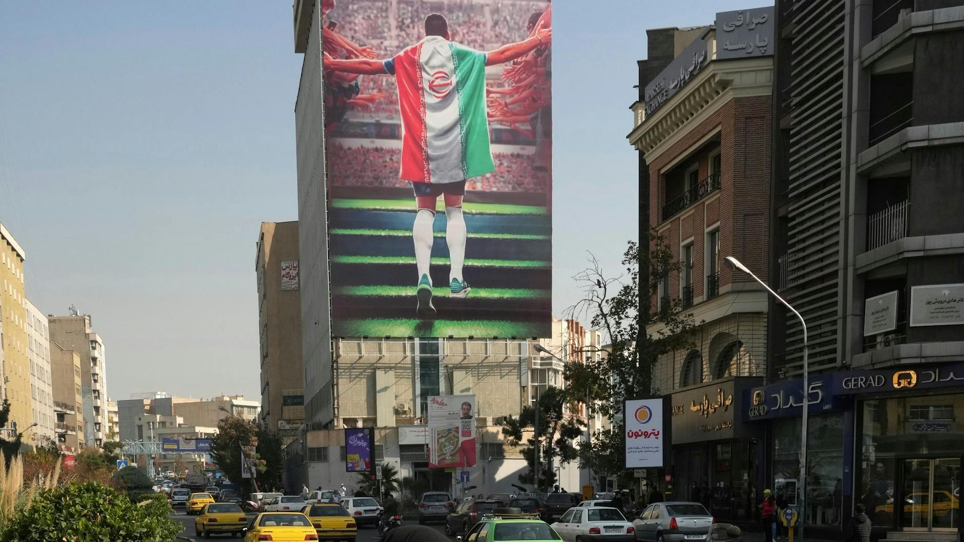 Ein Plakat zeigt einen Fußballspieler mit der Nationalflagge an einem Gebäude in Teheran.