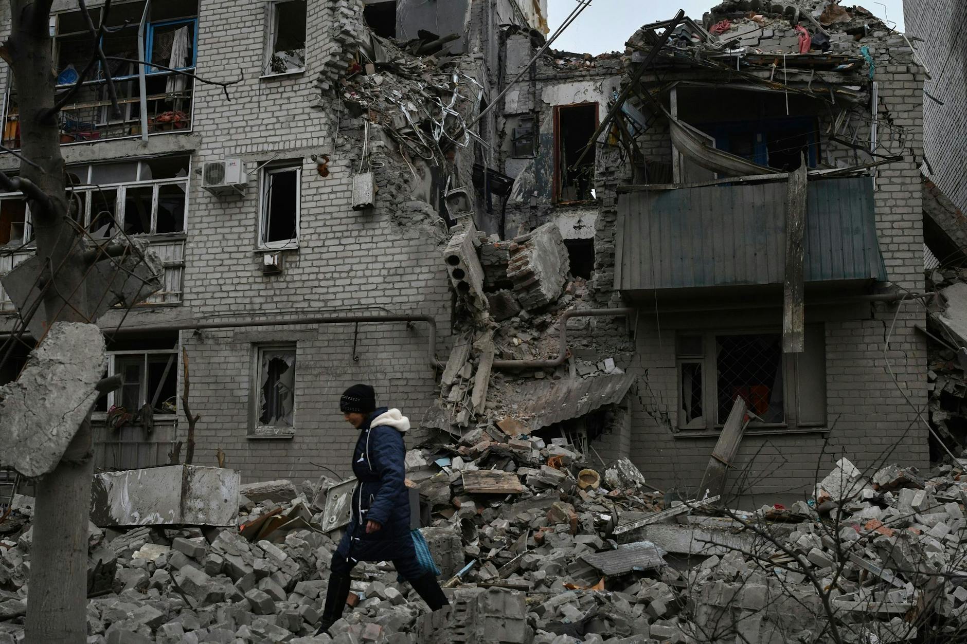 Eine Frau geht nach einem russischen Luftangriff in Tschassiw Jar an den Trümmern eines zerstörten Hauses vorbei.
