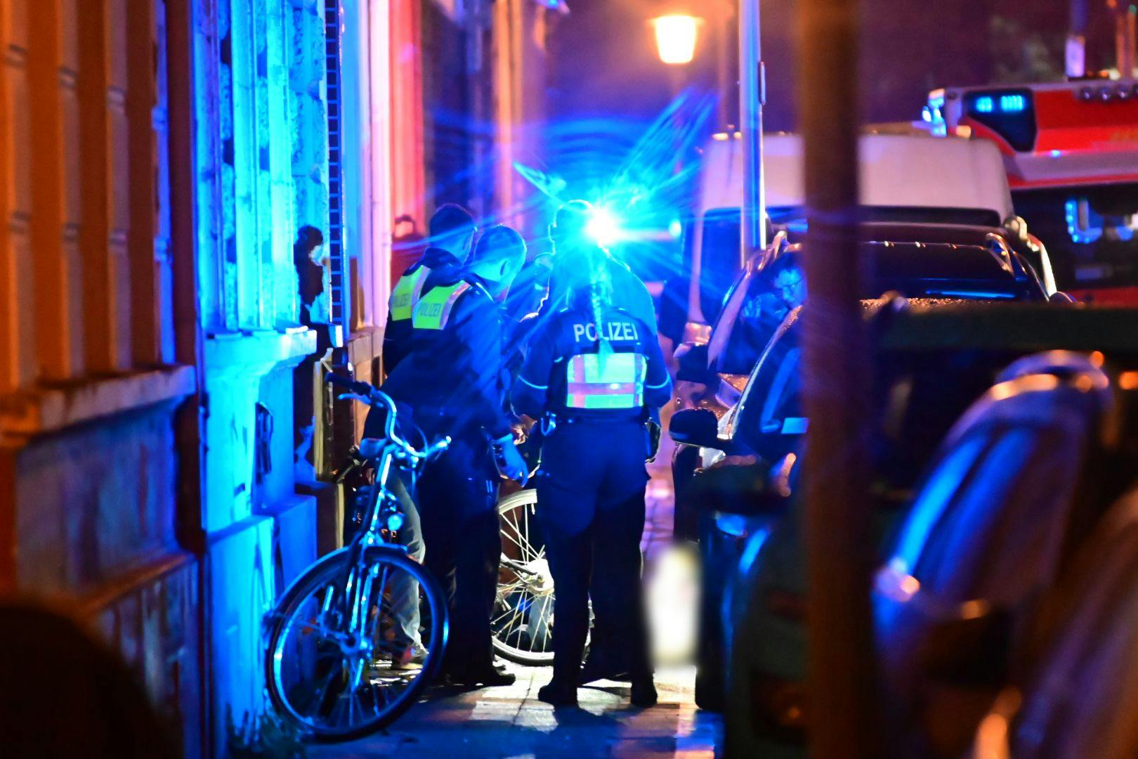 Polizisten stehen auf einem Geweg neben dem Toten. In der Krefelder Innenstadt ist am Montagabend ein Mann auf offener Straße erschossen worden.