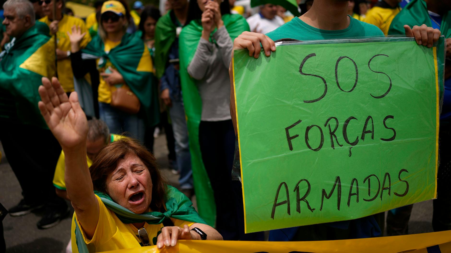 Ein Mann zeigt ein Plakat, mit dem er den Streitkräften ein SOS sendet. Ein Putsch-Aufruf.