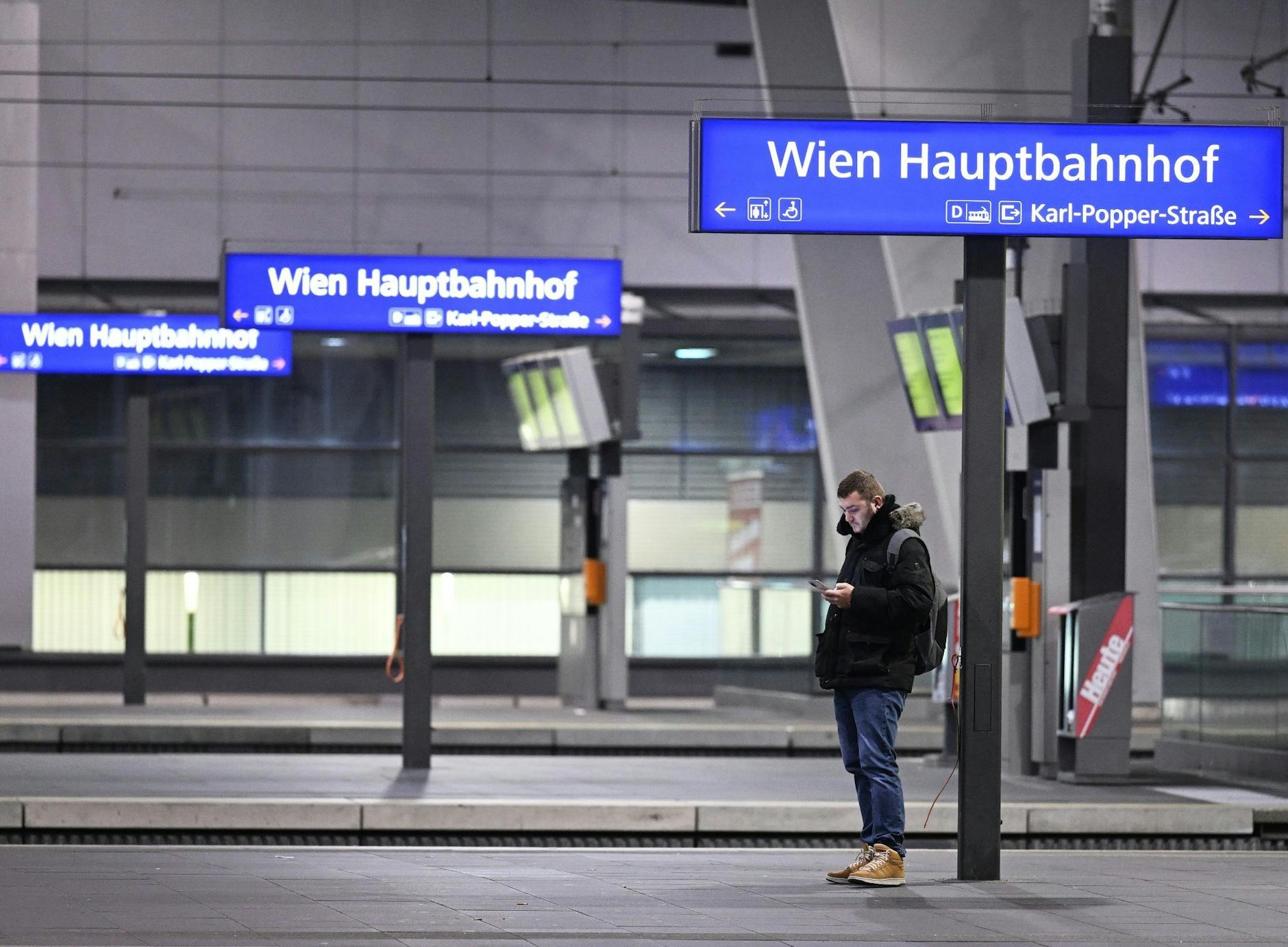 Ein Mann blick auf sein Smartphone an einem Bahnsteig im Hauptbahnhof Wien.
