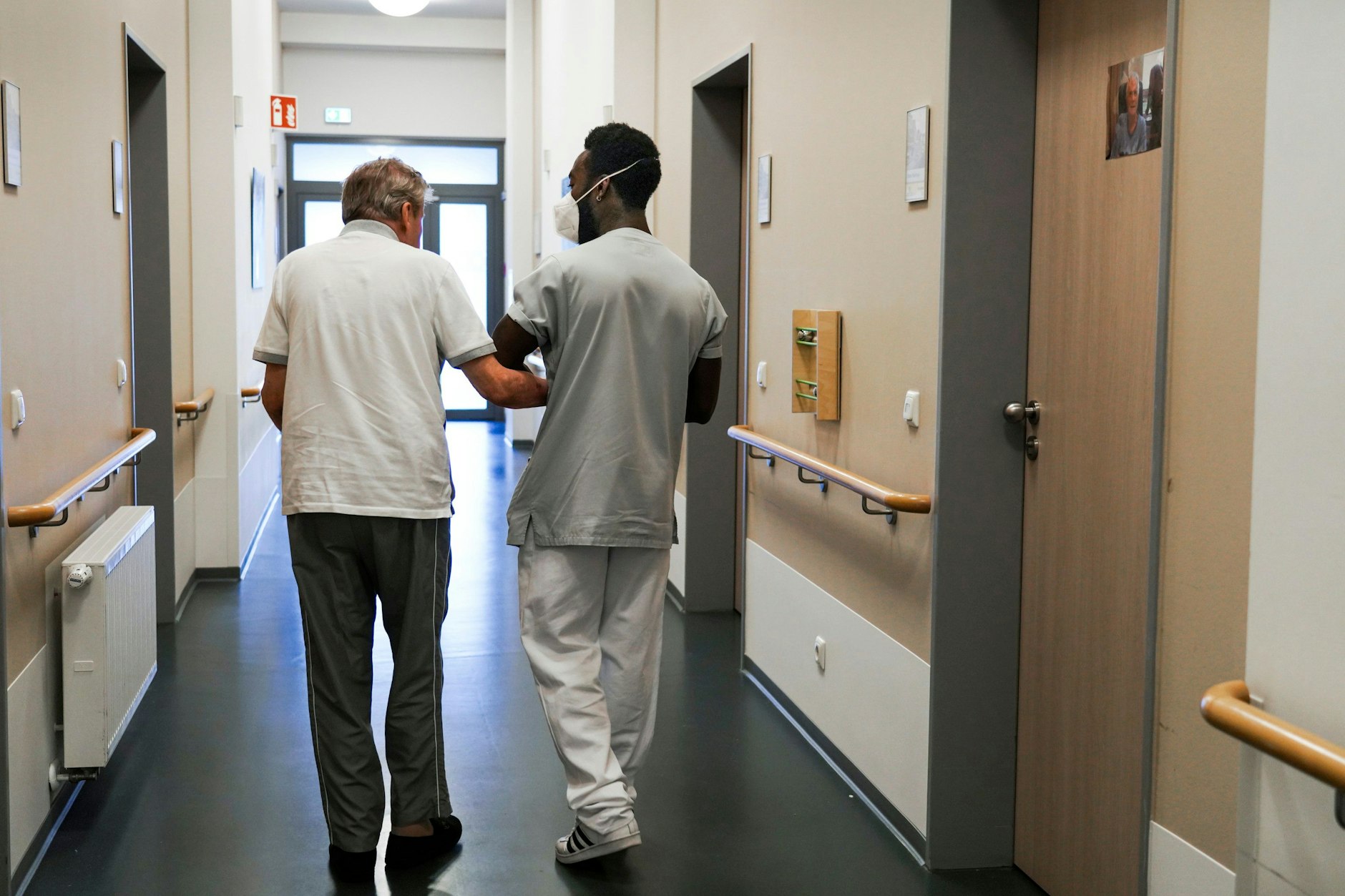 Ein Pfleger führt einen Heimbewohner über einen Gang: Viele Pflegekräfte fallen in diesem Jahr erkrankt aus.