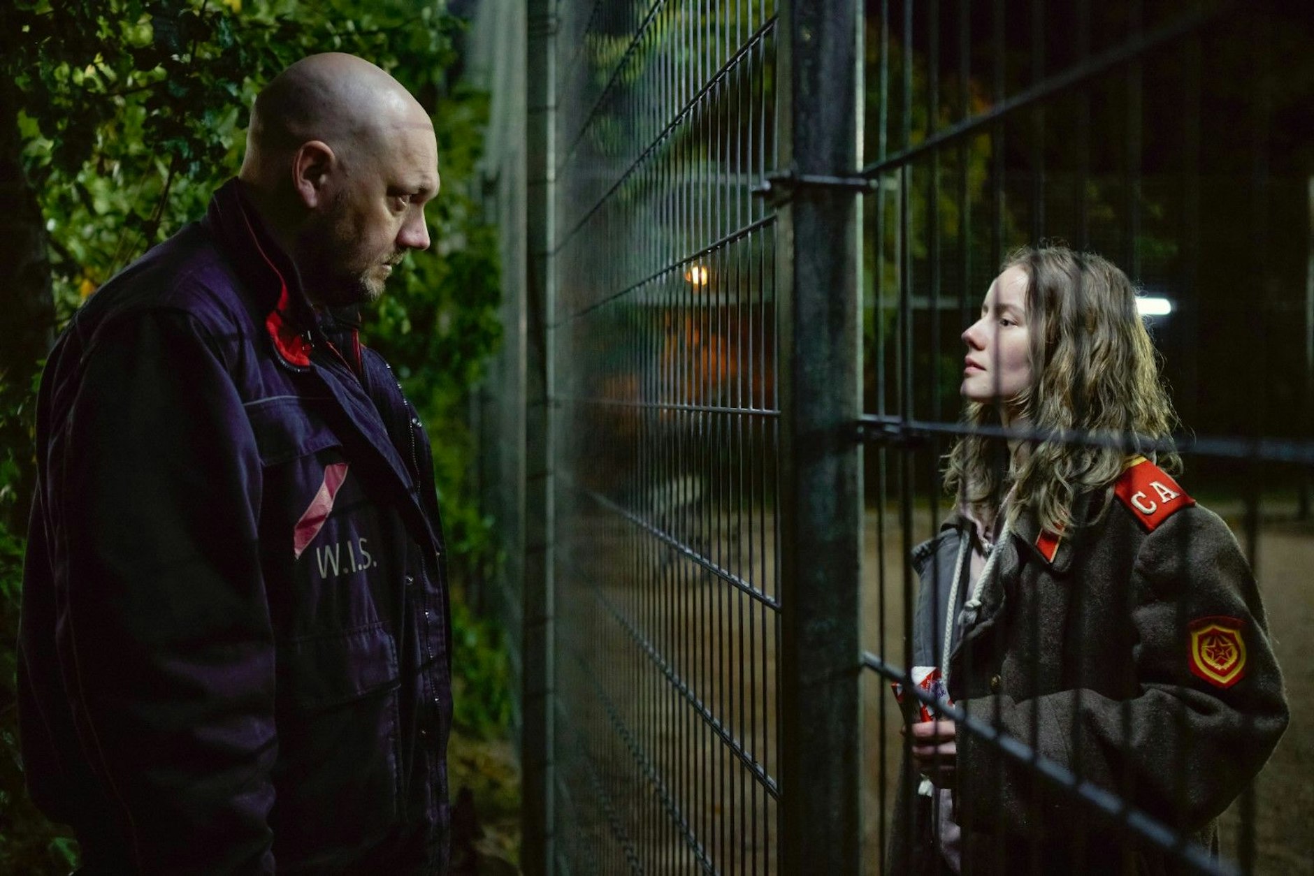 
Der Wachmann Erik (Charly Hübner) möchte das Mädchen (Irina Starshenbaum) hinter dem Zaun kennenlernen.