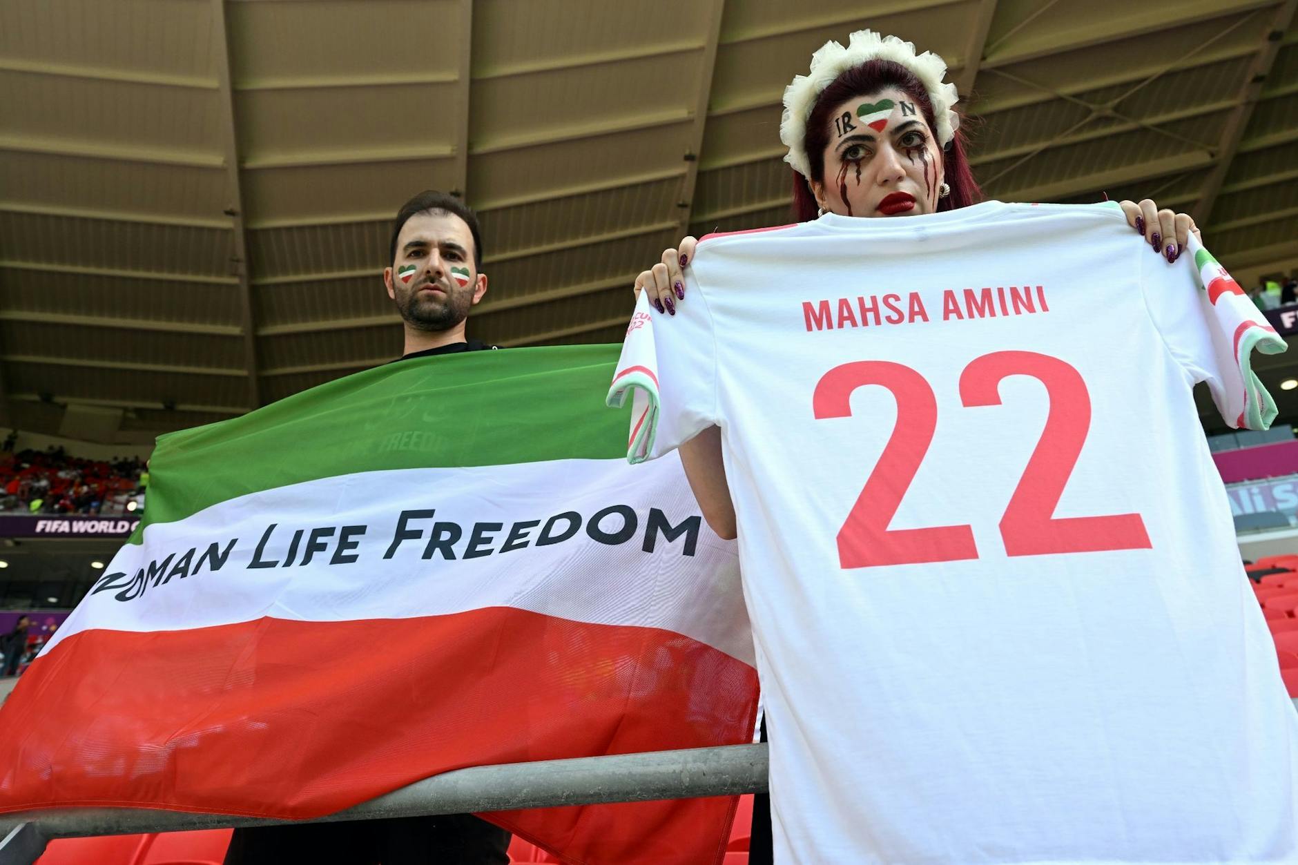 ARCHIV - Iraner protestieren vor dem Spiel und halten eine Flagge mit der Aufschrift "Women Life Freedom".
