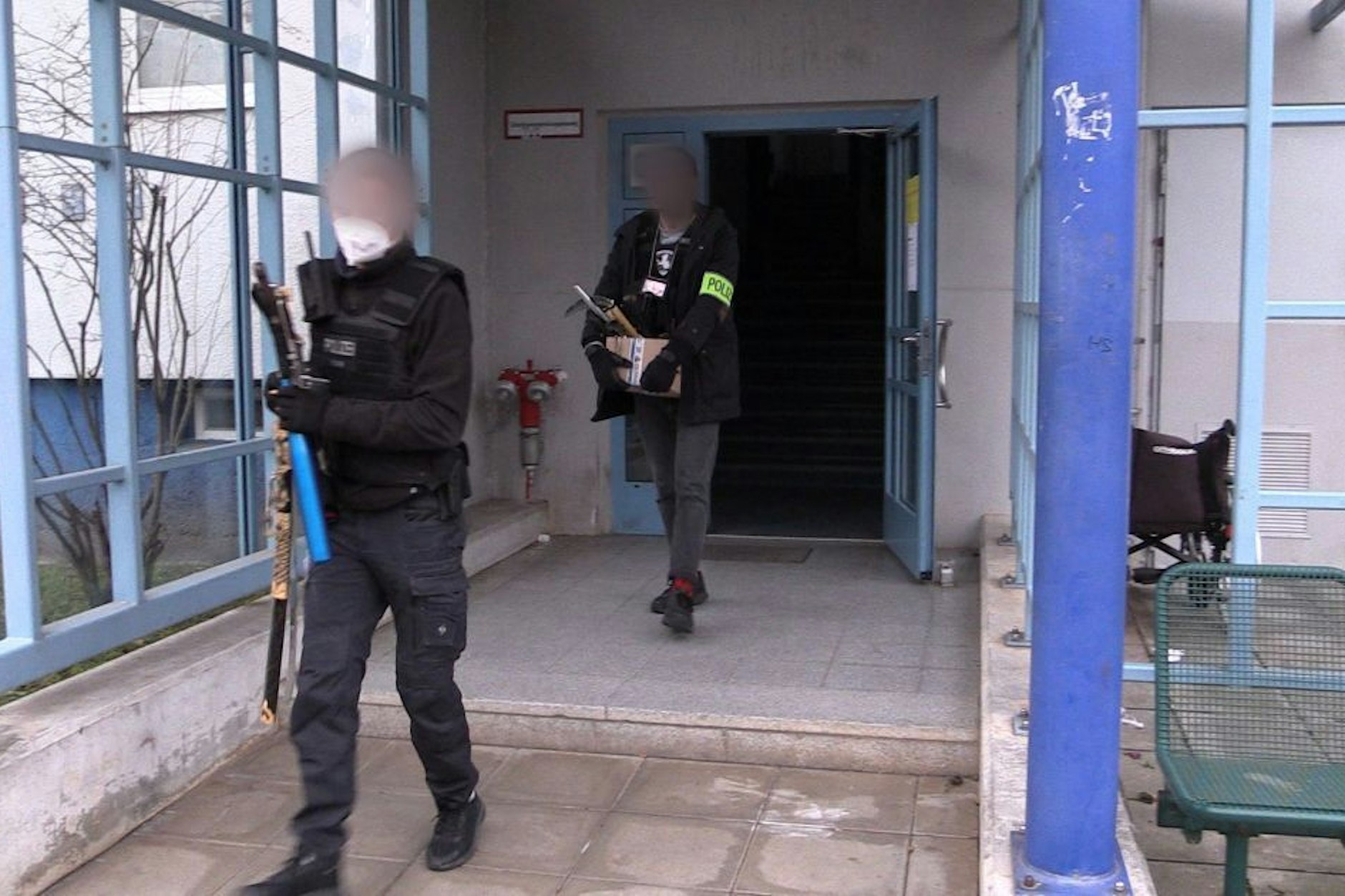 Polizisten verlassen mit beschlagnahmten Beweismitteln nach einer Durchsuchung ein Haus.&nbsp;