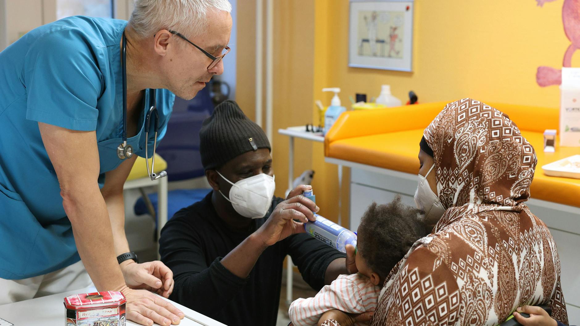 Dr. Lüder lässt Baba Barry üben, wie er den Inhalator für seine Tochter halten soll.