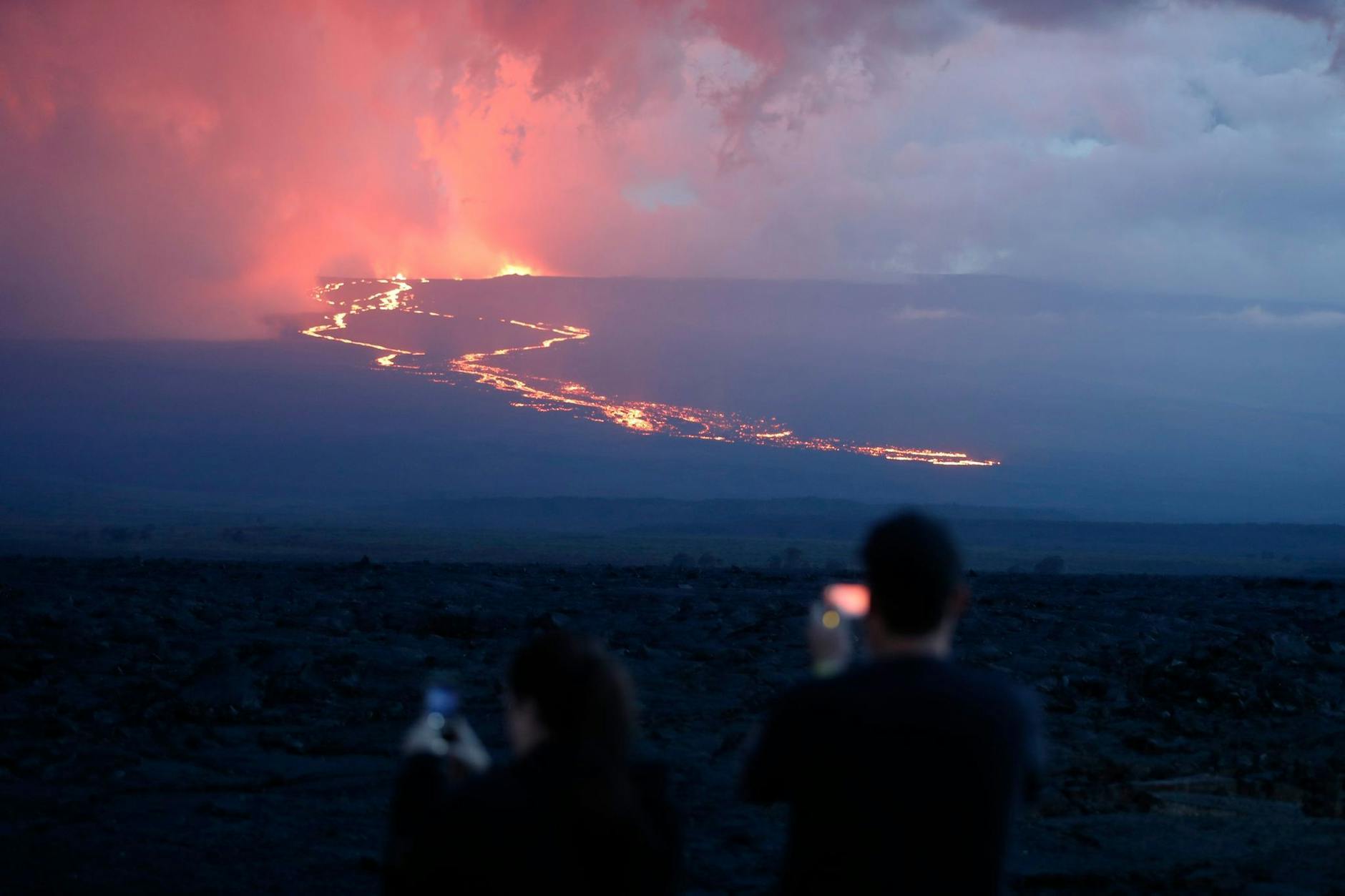 Zuschauer beobachten den Lavastrom, der bei der Eruption des Mauna Loa in der Nähe von Hilo, Hawaii, den Berg hinunterfließt.