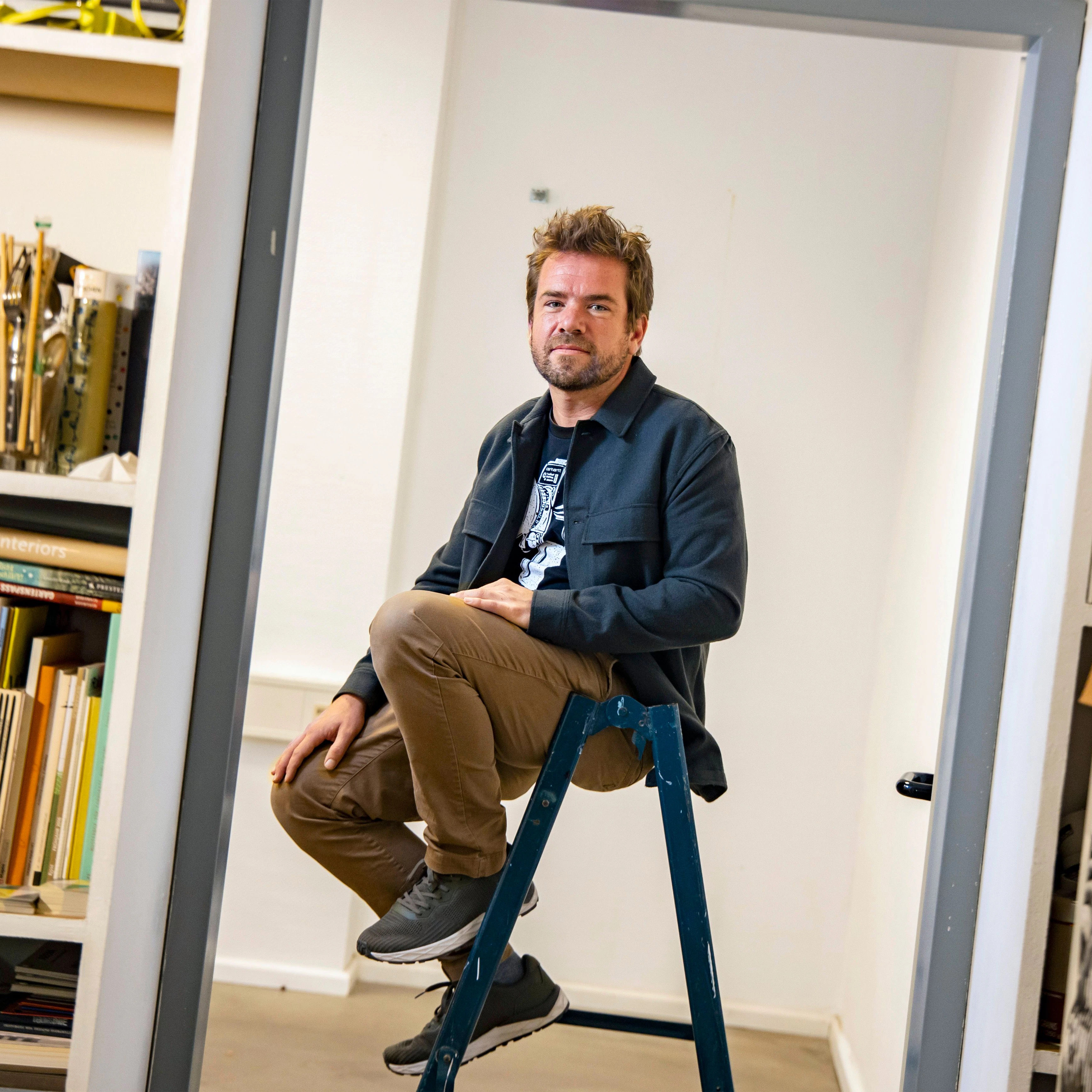 Grafikdesigner Vincent Kraft am Durchgang zum leer geräumten Teil seines Büros.