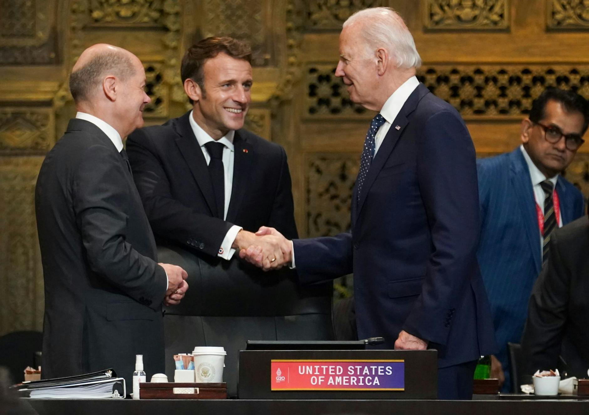 US-Präsident Joe Biden (r) und Frankreichs Präsident Emmanuel Macron begrüßen sich während des G20-Gipfels in Indonesien, daneben steht Bundeskanzler Olaf Scholz. pa