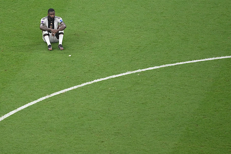 Antonio Rüdiger sitzt verloren auf dem Rasen im Al-Bayt-Stadium.