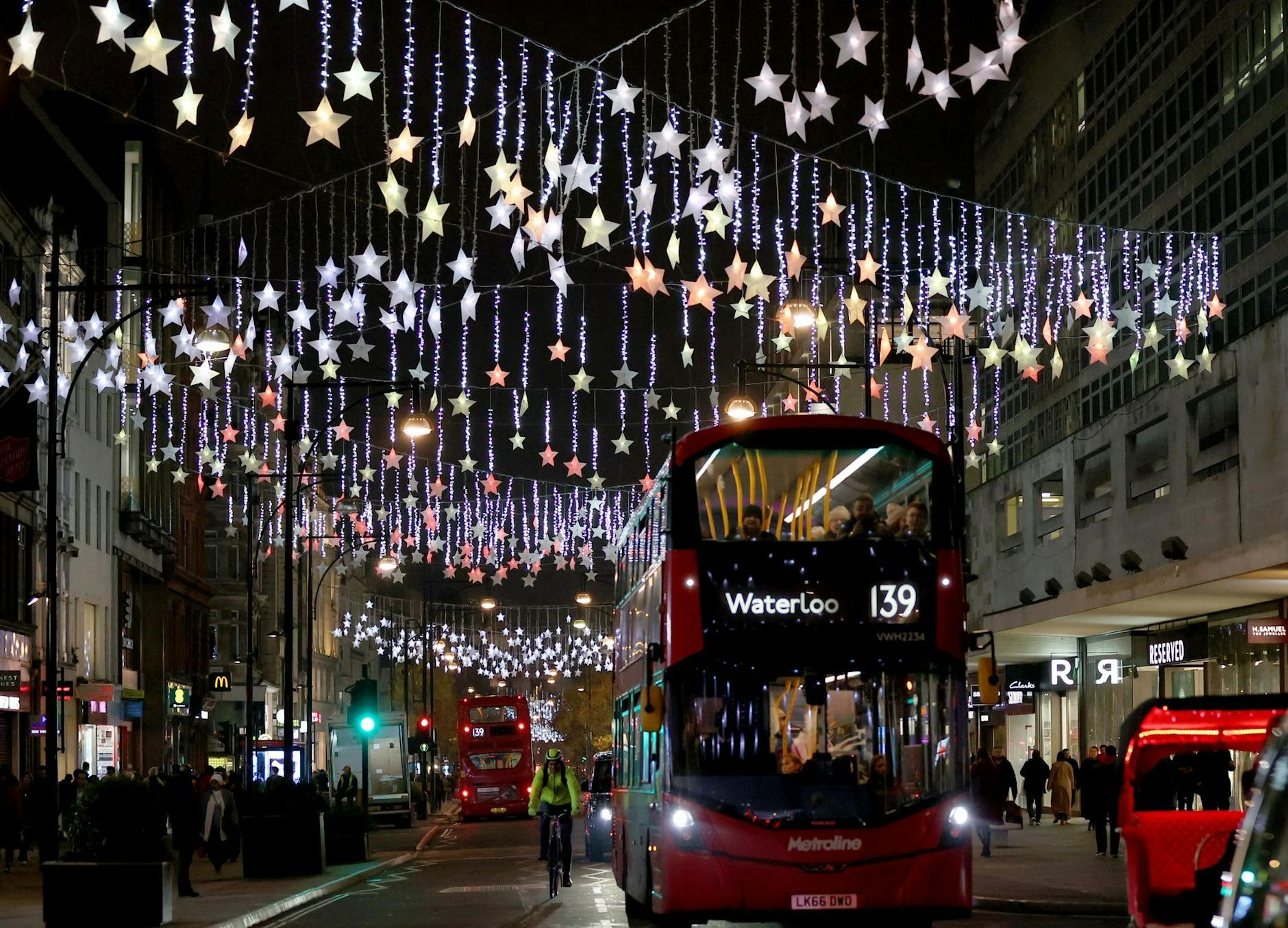 Ein Doppeldeckerbus fährt auf der weihnachtlich beleuchteten Einkaufsstraße Oxford Street in London.