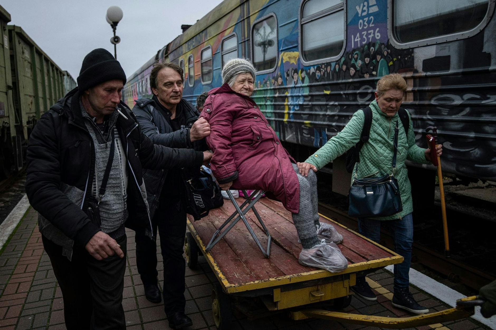 Angehörige einer älteren ukrainischen Frau transportieren sie zu einem Evakuierungszug in Cherson.