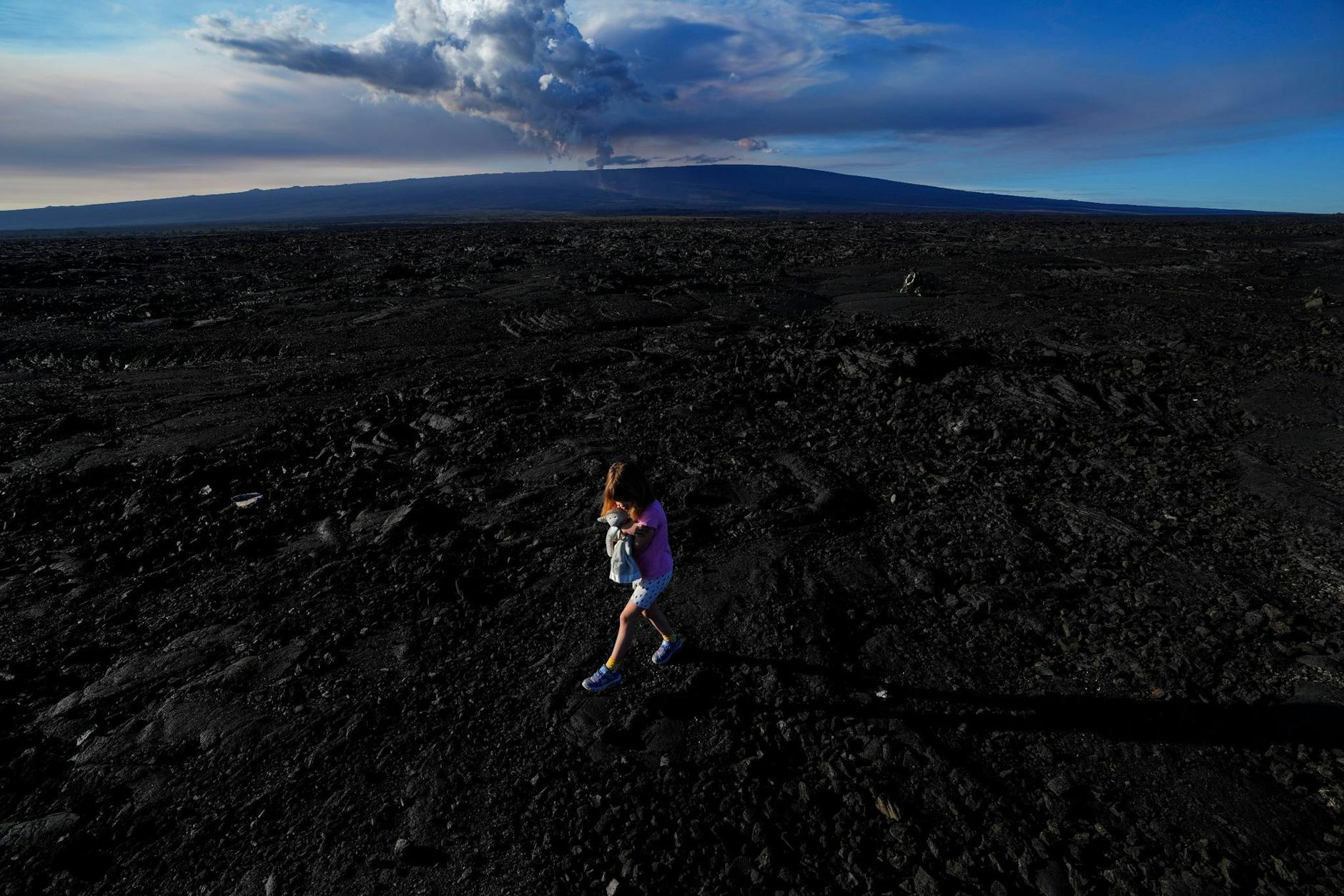 Für ihren Spaziergang über gehärtetes Lavagestein von einem früheren Ausbruch des Vulkans Mauna Loa auf Hawaii hat eine junge Touristin aus Kanada ein Stofftier mitgebracht.
