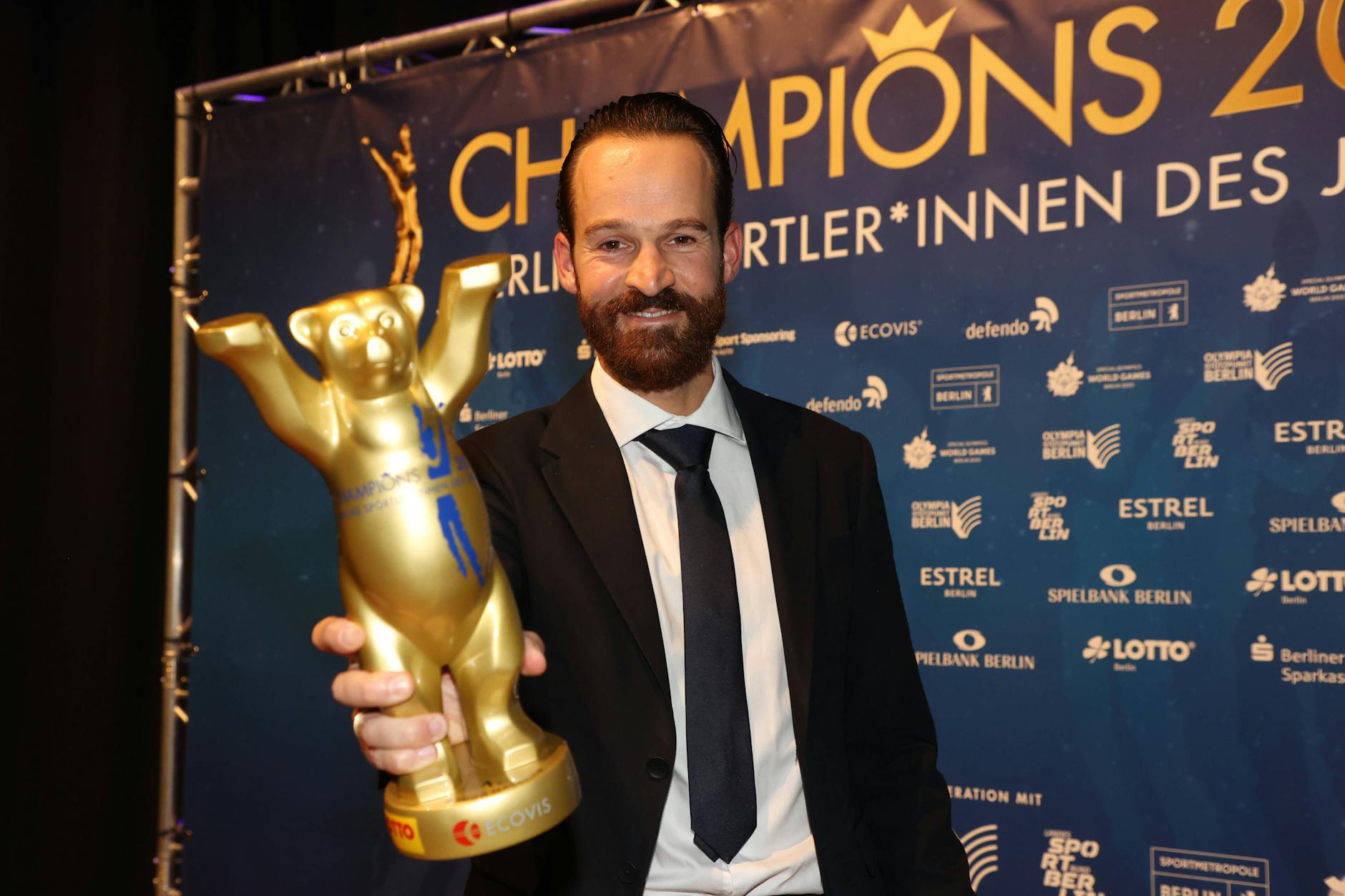 Radrennfahrer Simon Geschke hält den Buddy-Bären in Gold als Berlins Sportler des Jahres 2022 in die Kamera.