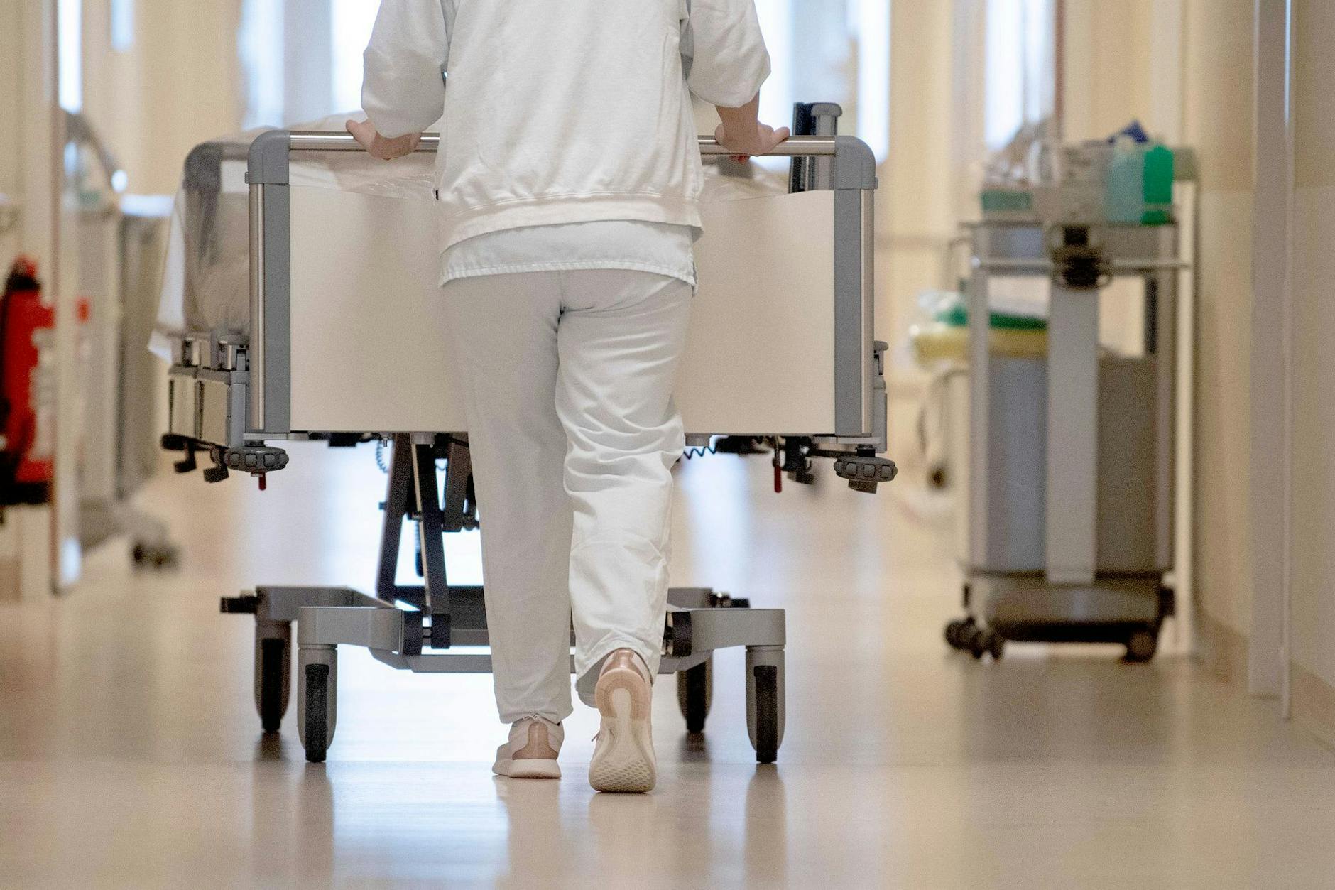 Eine Krankenpflegerin schiebt ein Krankenbett durch einen Flur. Patientenschützer warnen vor „Verschiebebahnhof“ bei Klinik-Tagesbehandlungen.