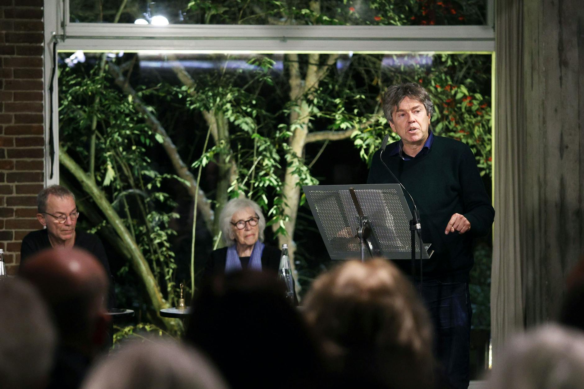 „3. Berliner Begegnung“ in der Akademie der Künste: Es spricht der Film- und Theaterregisseur Andres Veiel, im Hintergrund das Moderatorenduo Thomas Heise und Nele Hertling.