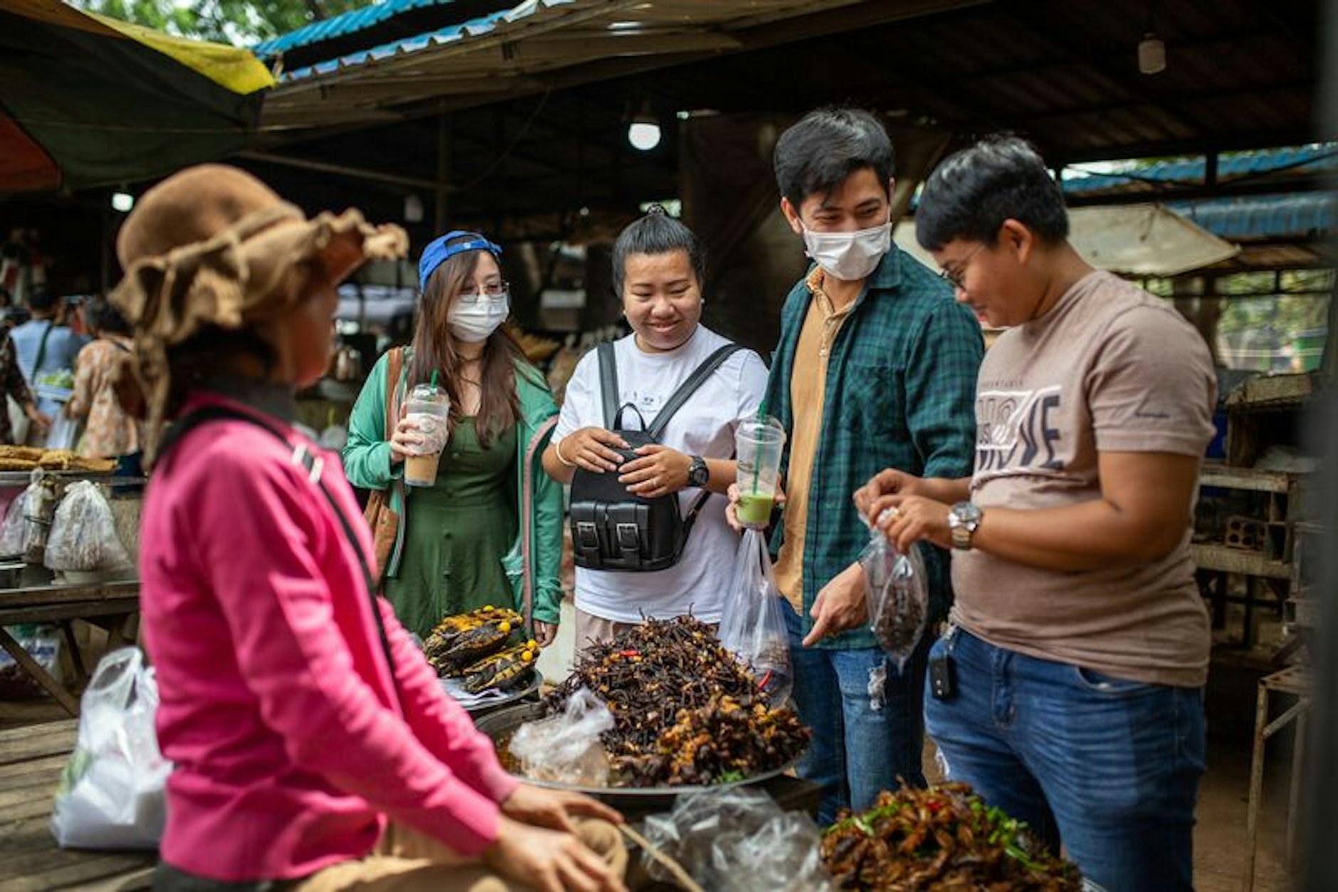 Marktbesucher kaufen gebratene Vogelspinnen, die auf dem Udong-Markt angeboten werden. In Kambodscha gelten gebratene Vogelspinnen in pikanter Sauce als Delikatesse.