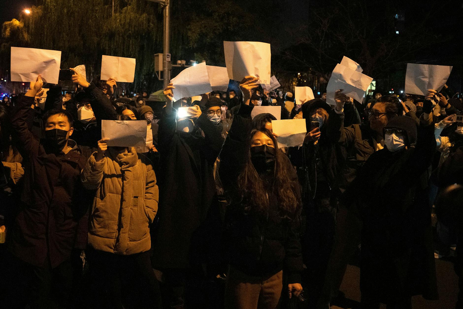 Demonstranten halten leere Papiere hoch, während sie protestieren.